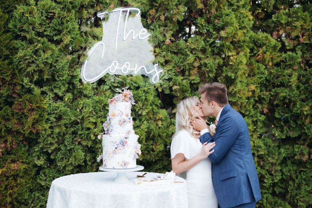 wedding cake with bride and groom and neon sign