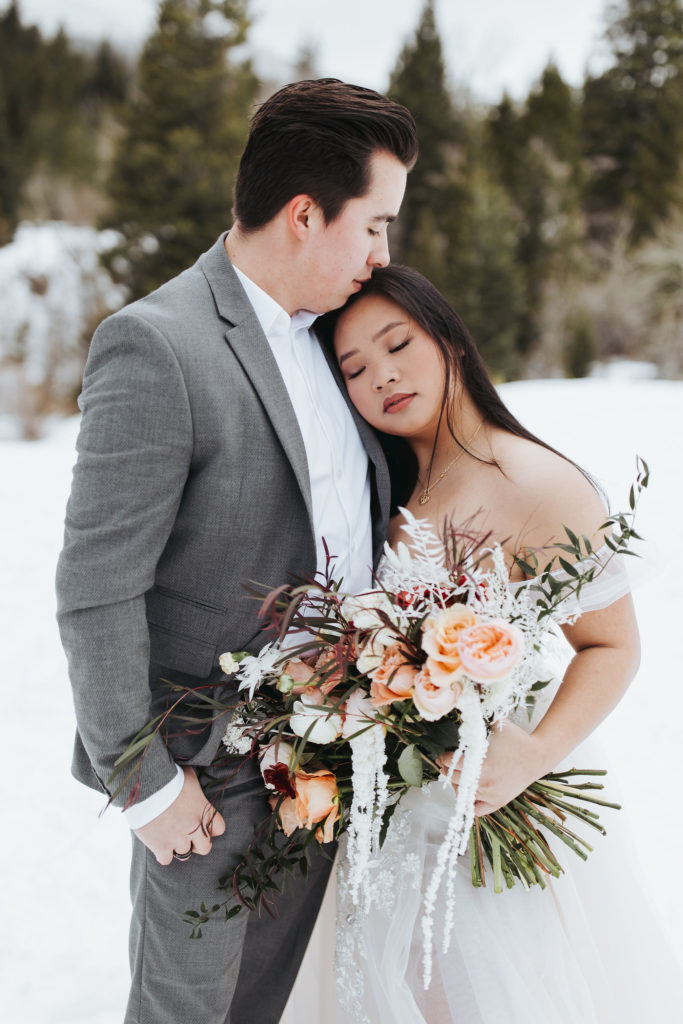 bride and groom on snowy mountain in utah