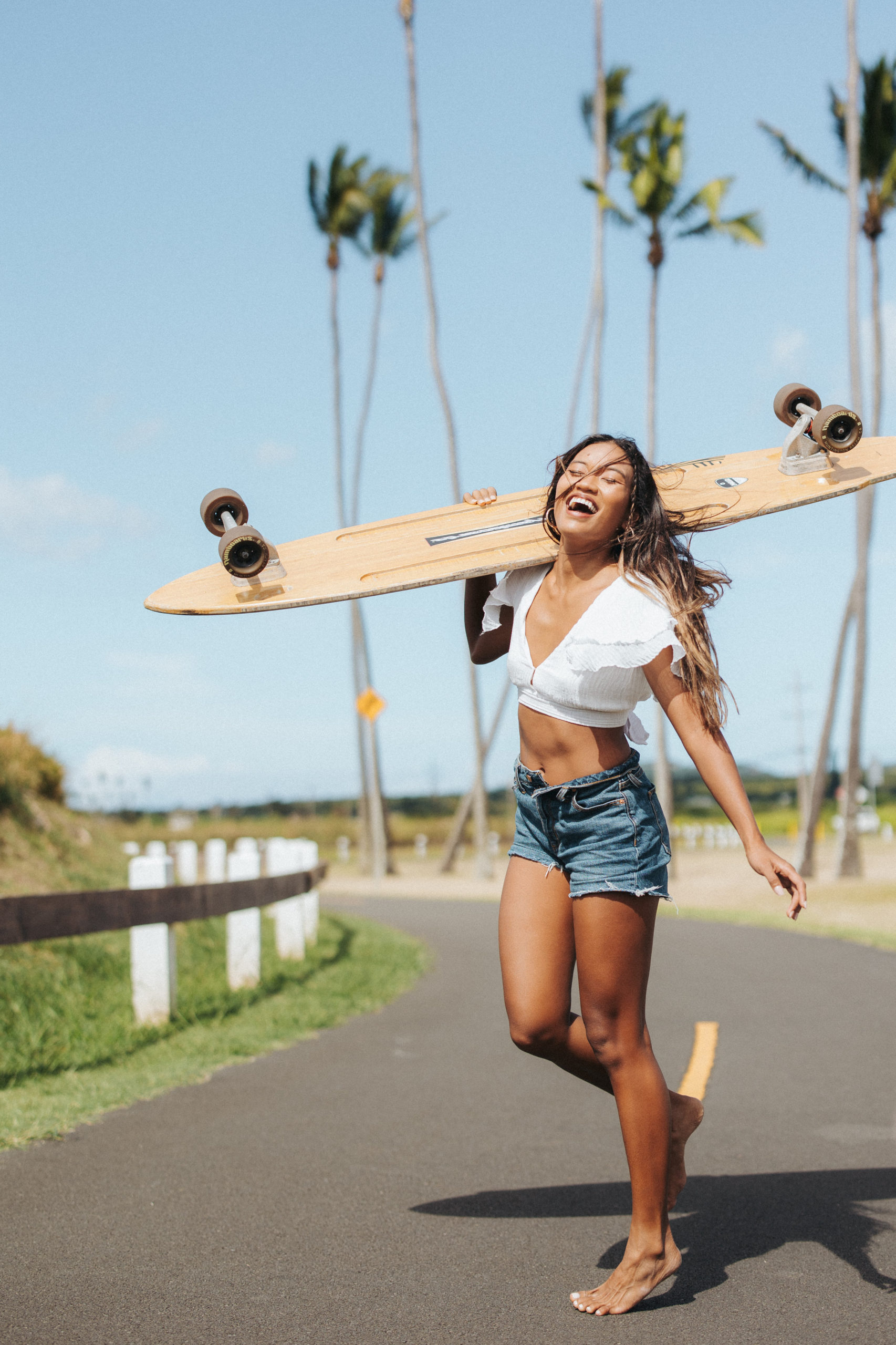 woman holding a longboard on her shoulder