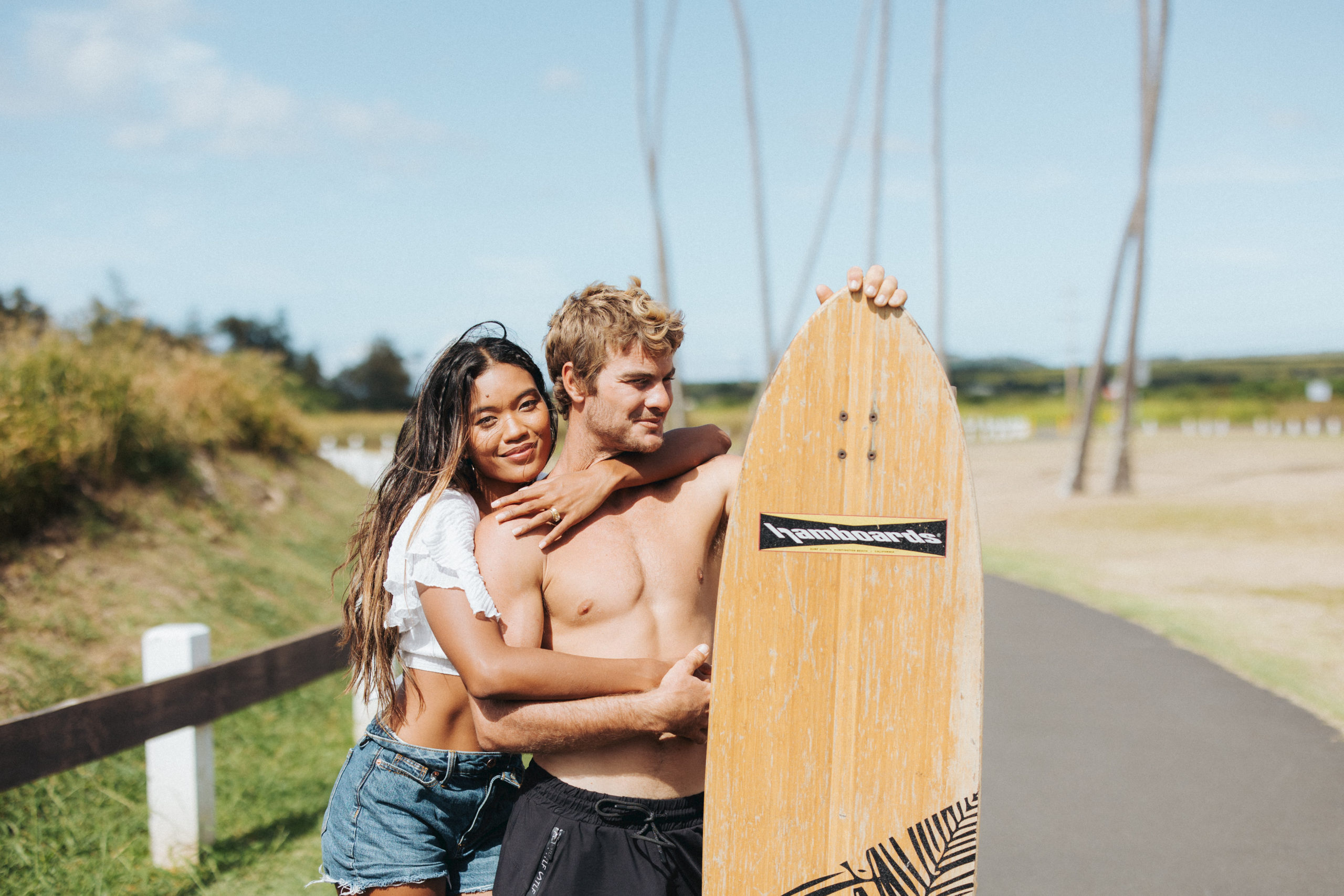 couple hugging and holding a longboard