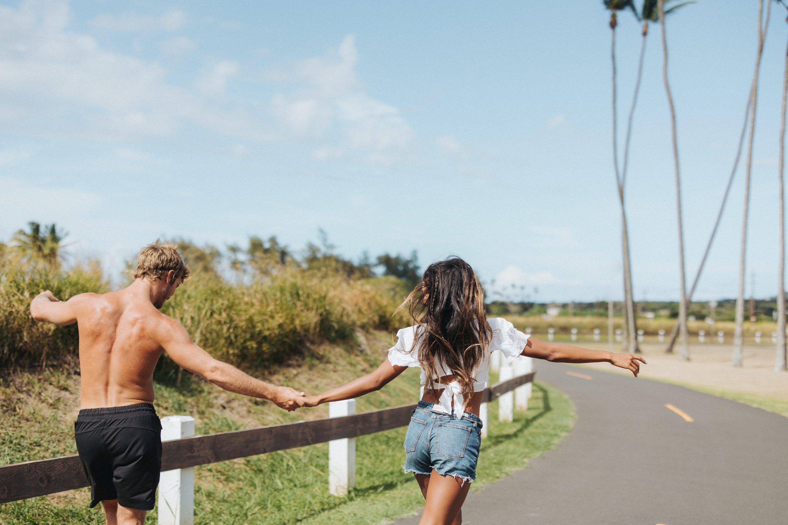couple running down a road toward palm trees