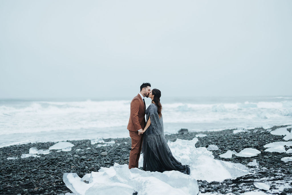 couple portrait standing on icy black rock beach