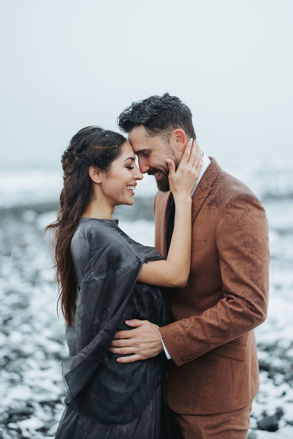 couple portrait kissing on icy black rock beach