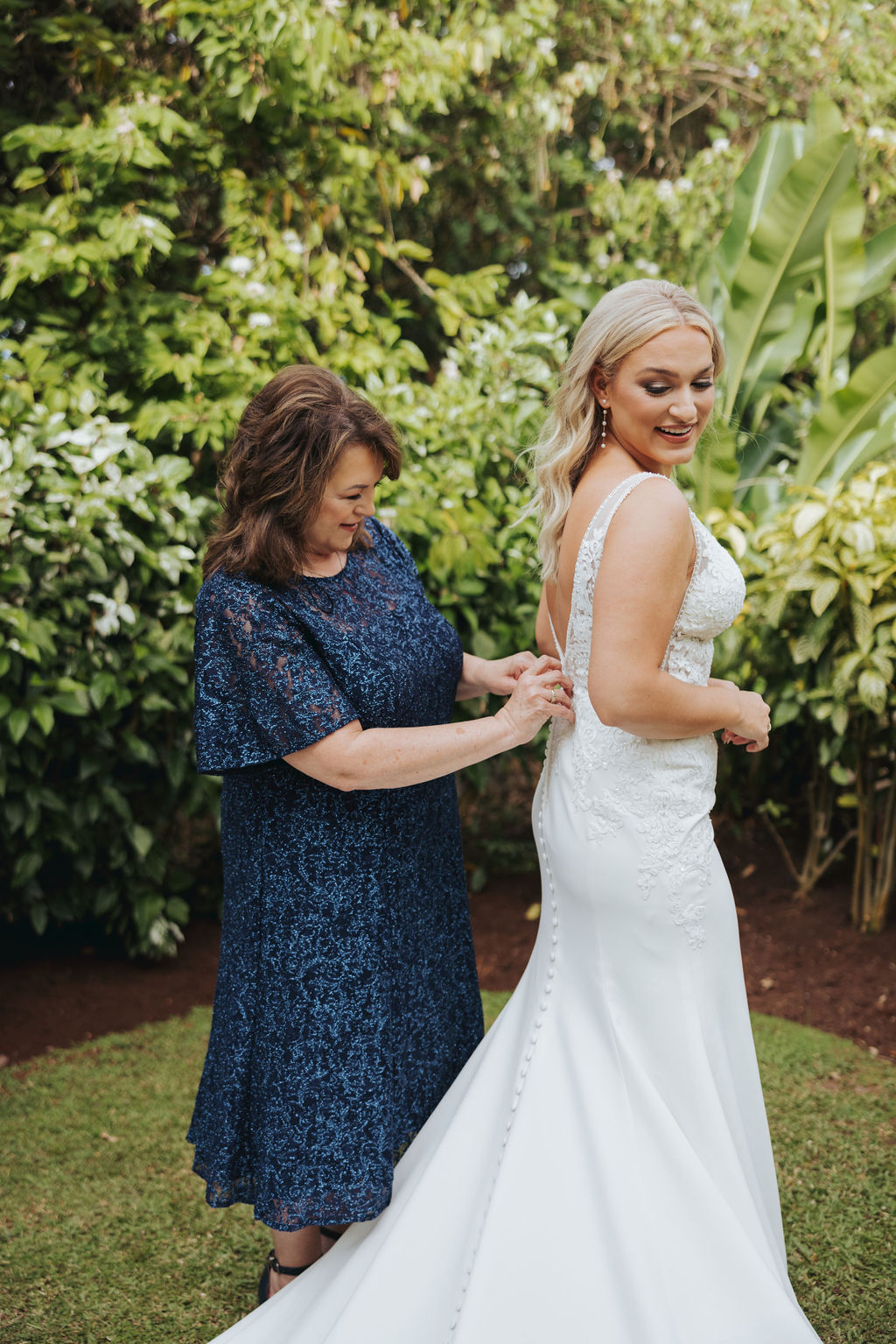 mother helping bride get into wedding dress