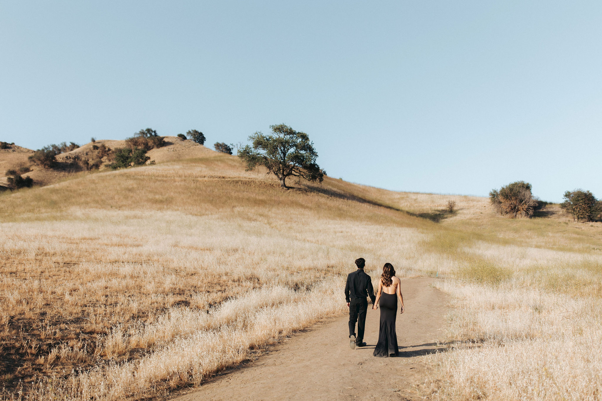 couple holding hands and walking up a grassy hill in Malibu Creek State Park