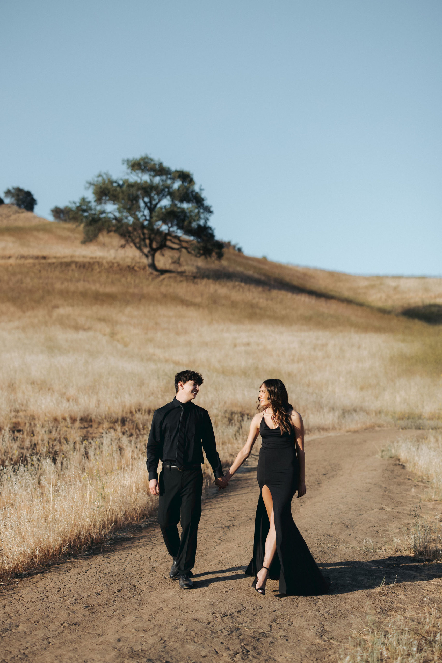 couple holding hands and walking up a grassy hill  in Malibu Creek State Park