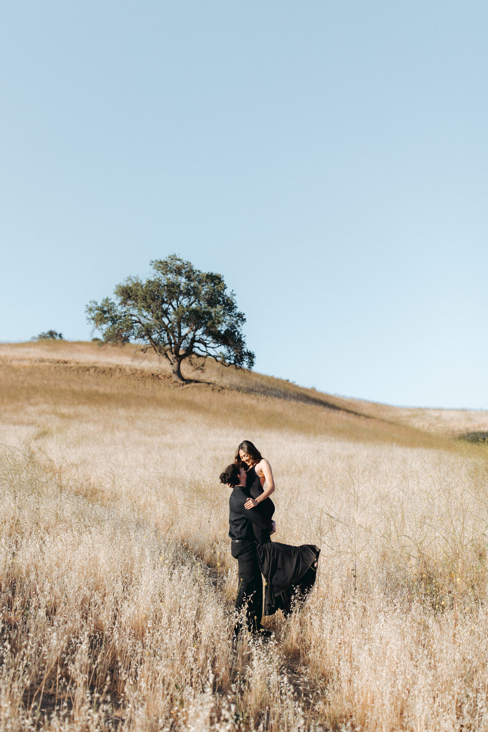 couple holding hands and walking up a grassy hill  in Malibu Creek State Park