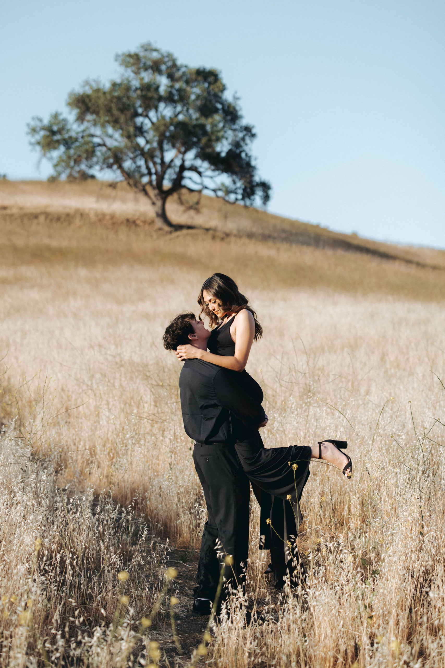 couple holding hands and walking up a grassy hill