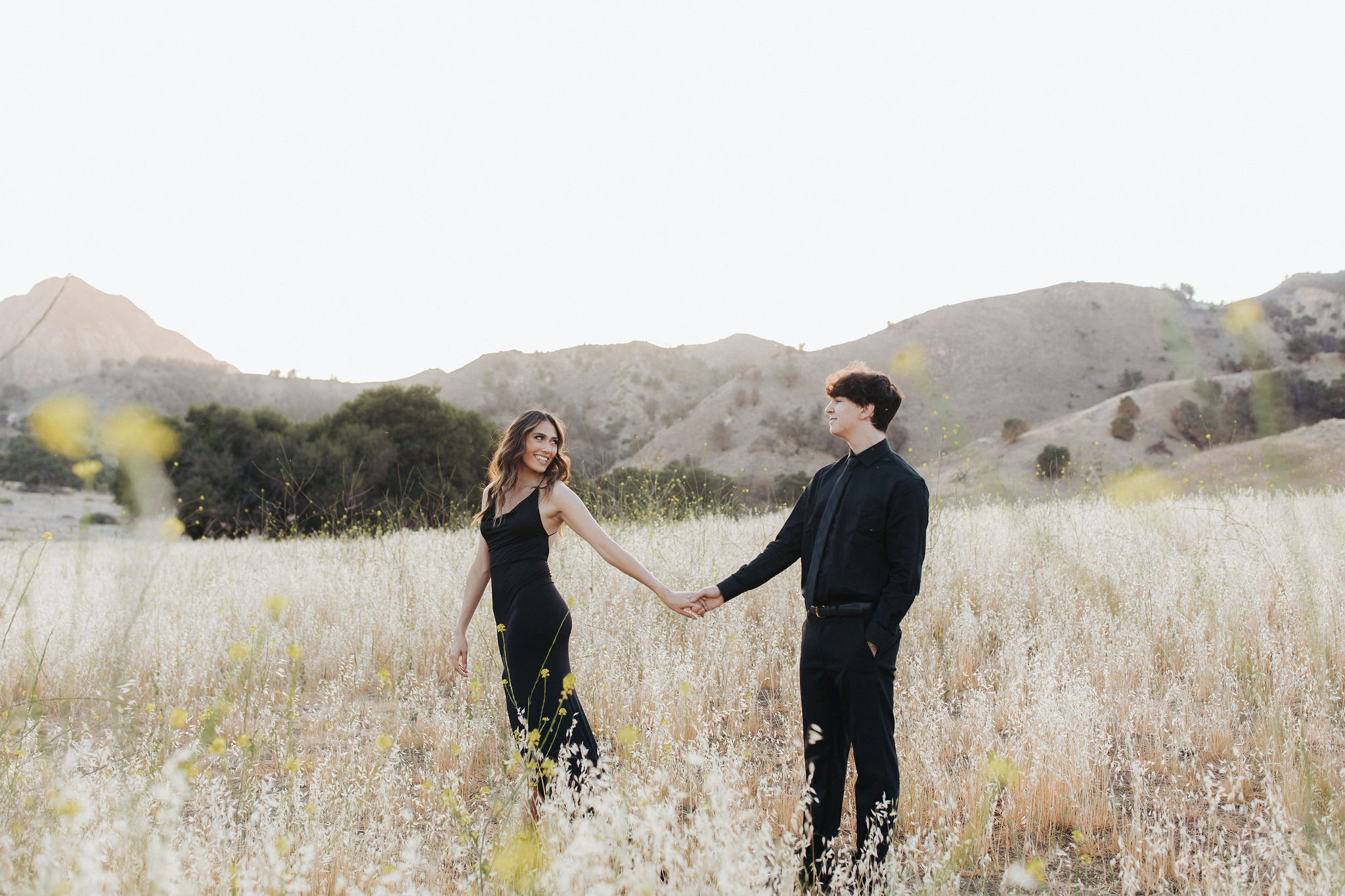 couple holding hands in front of mountains in Malibu Creek State Park