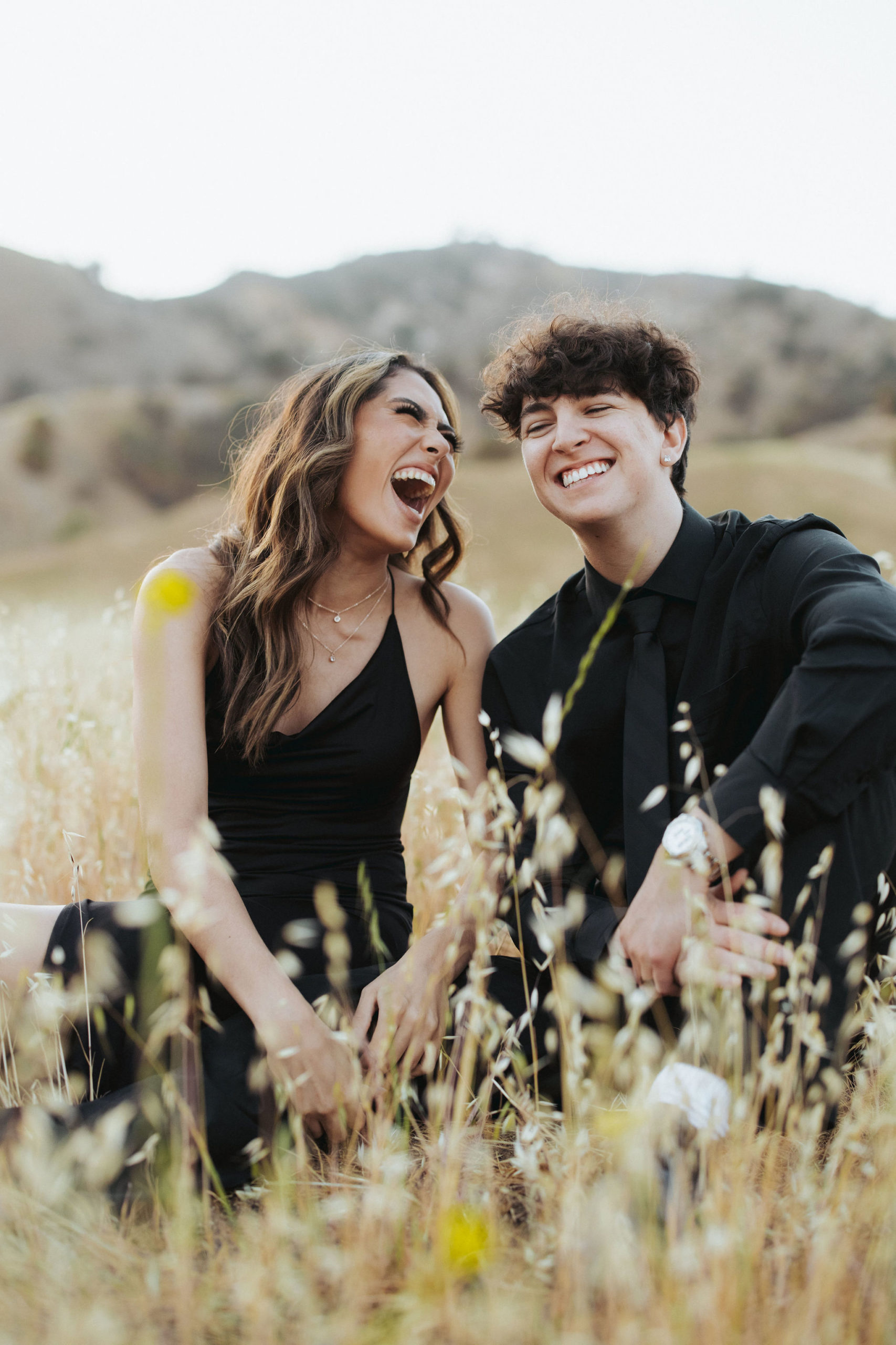 couple sitting in a field in front of mountains in Malibu Creek State Park
