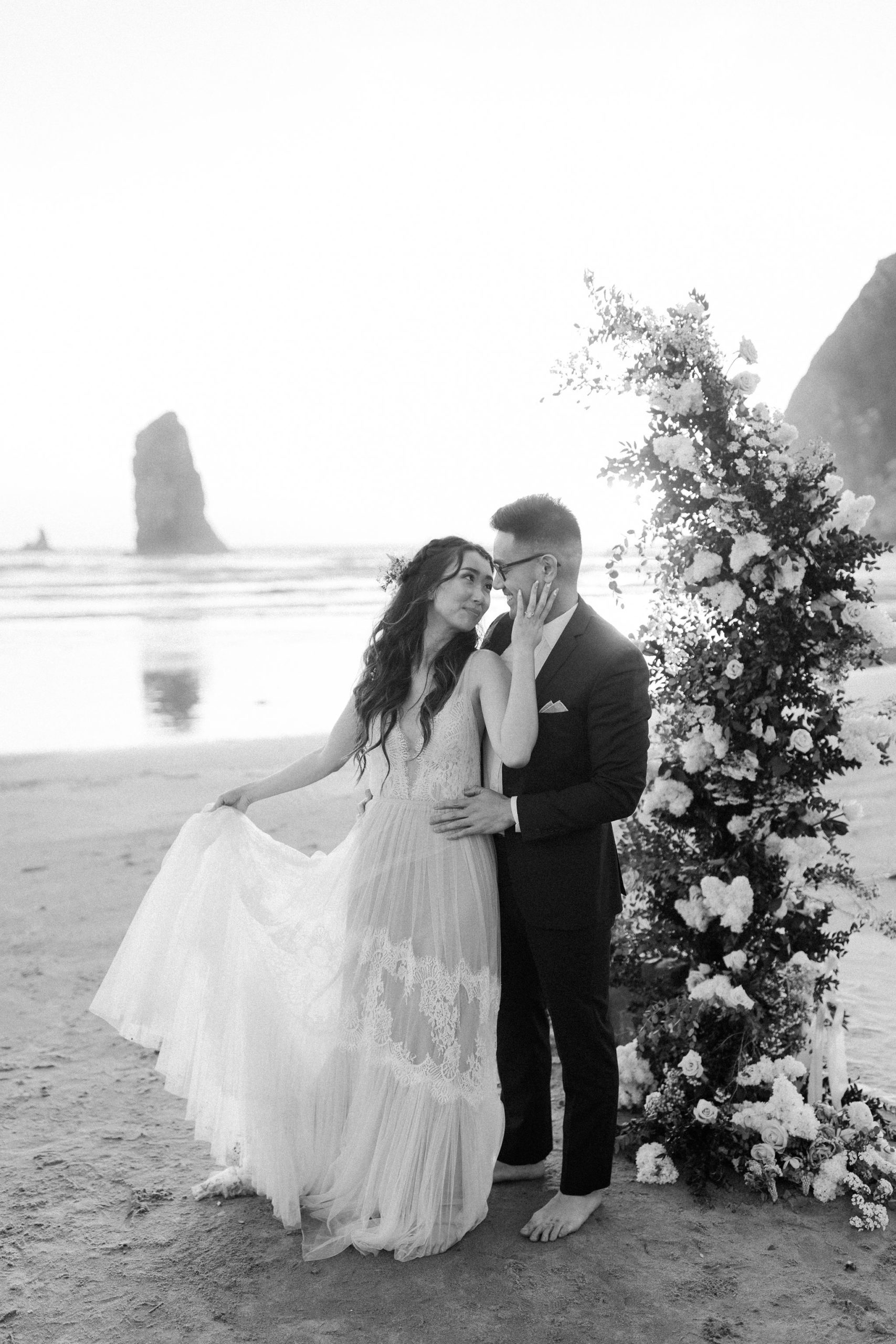 bride and groom portrait on beach with flower arch and candles