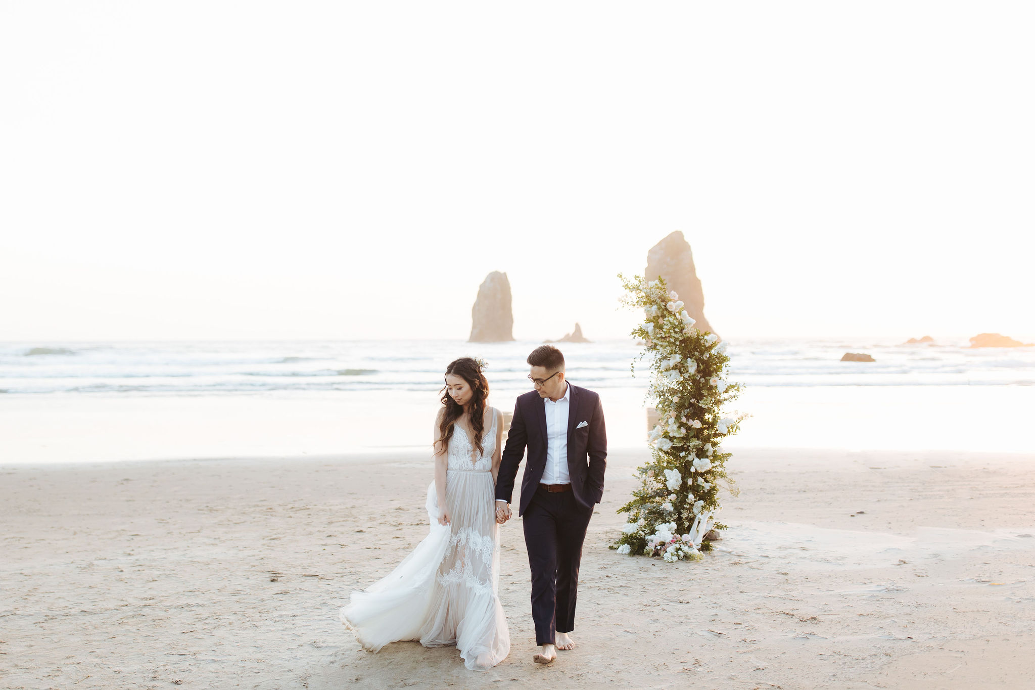bride and groom elopement portraits on Oregon Coast  beach with flower arch and candles