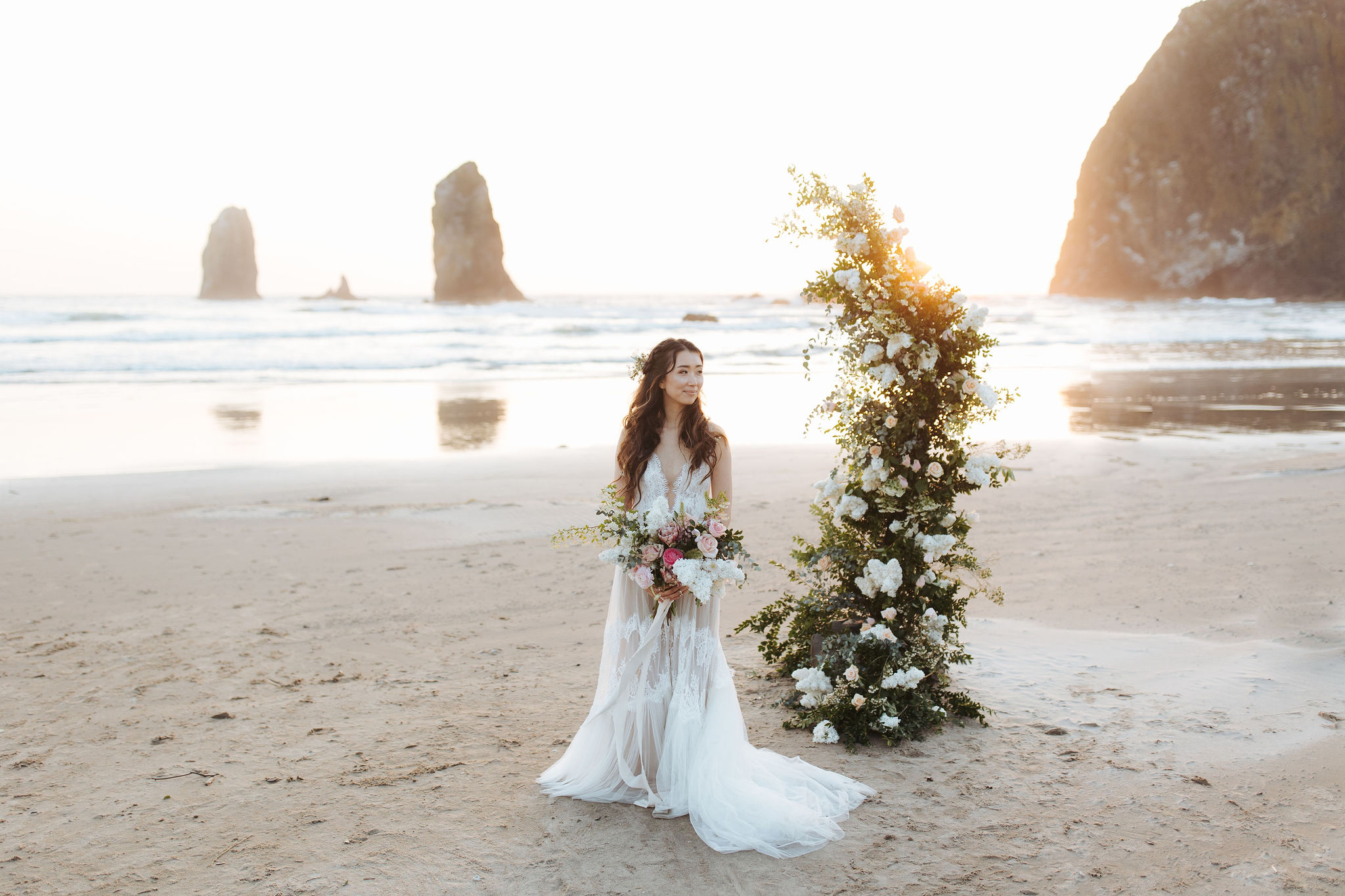 bride  elopement portraits on Oregon Coast beach with flower arch and candles