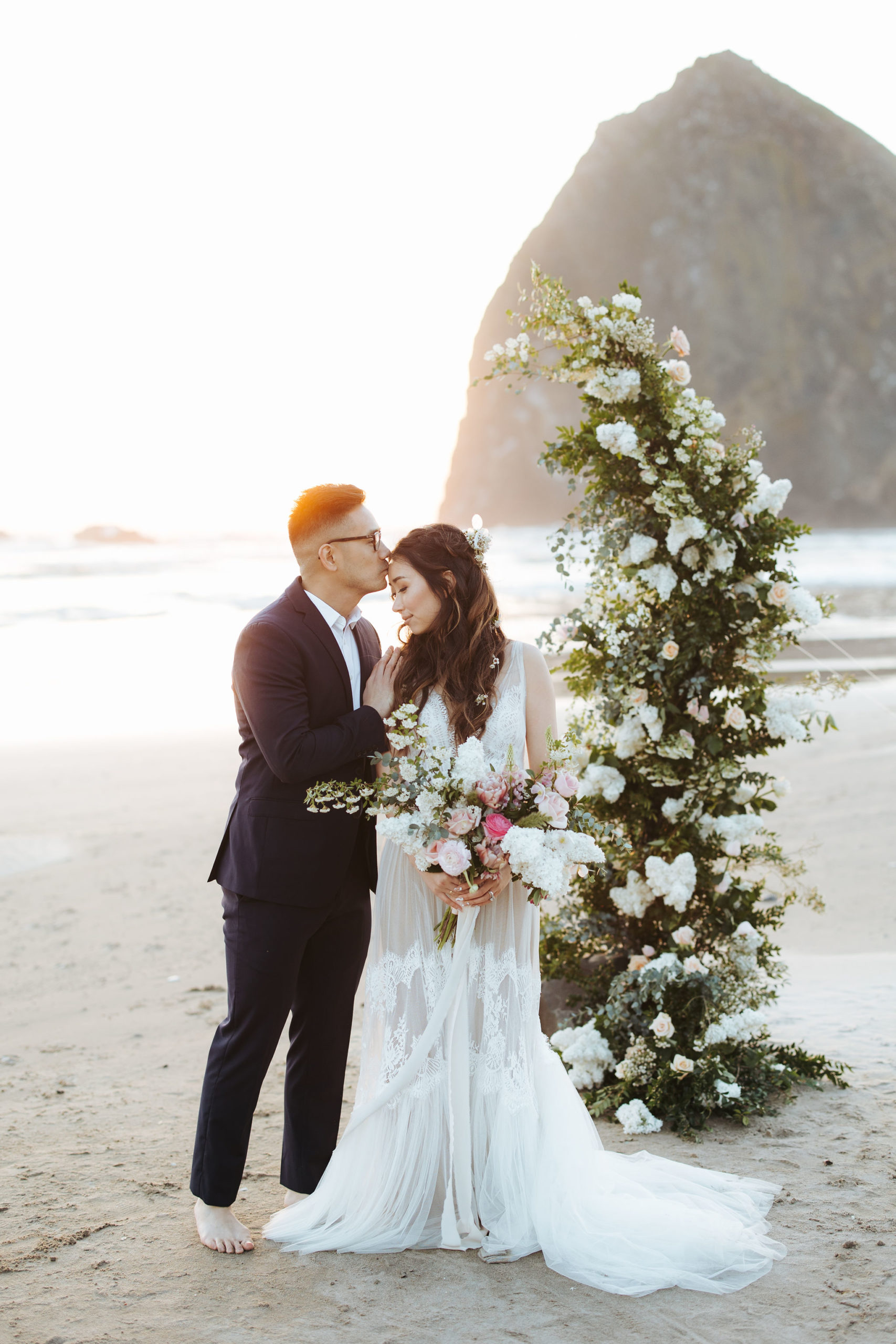 bride and groom portrait on beach with flower arch and candles