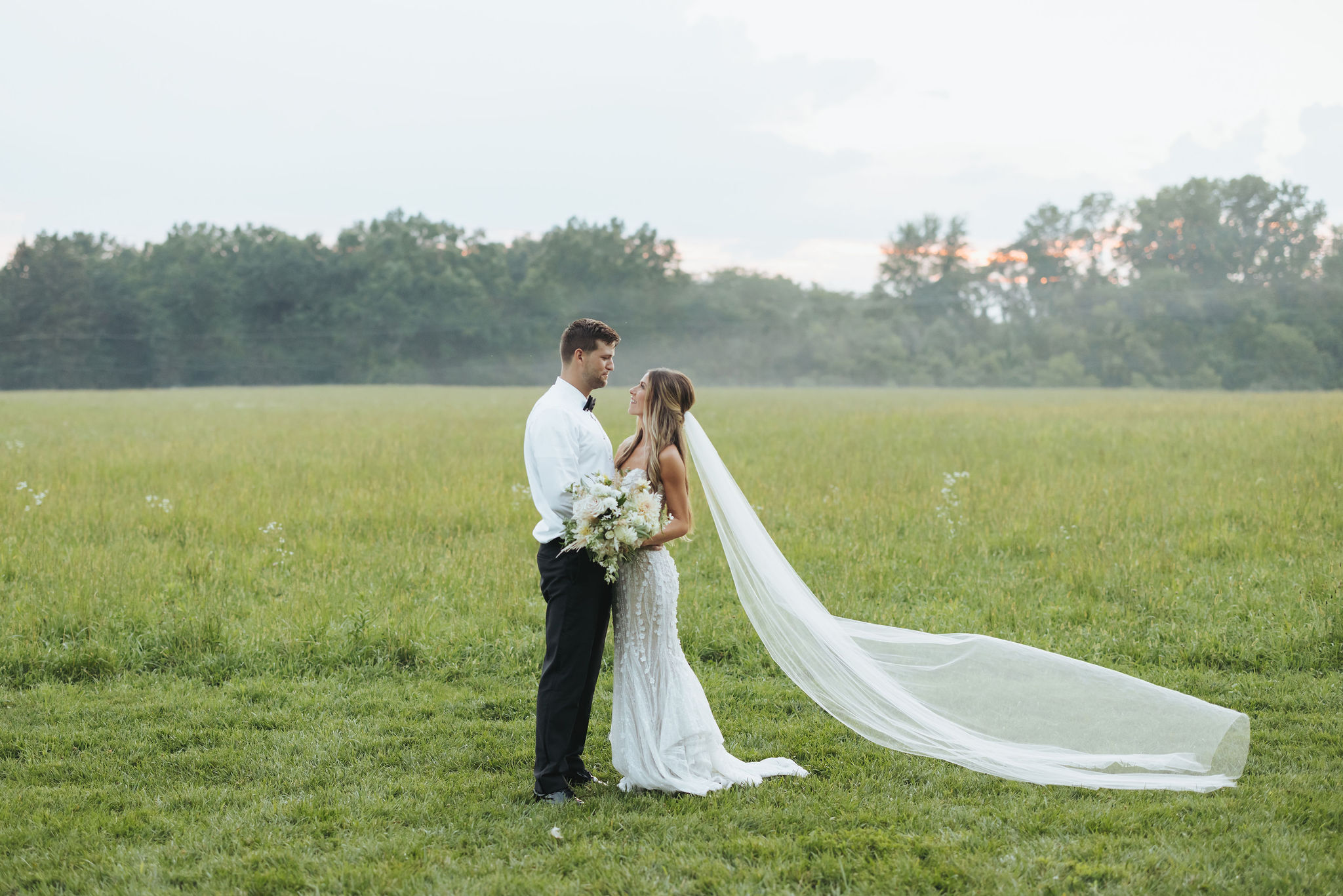bride and groom posing in a field