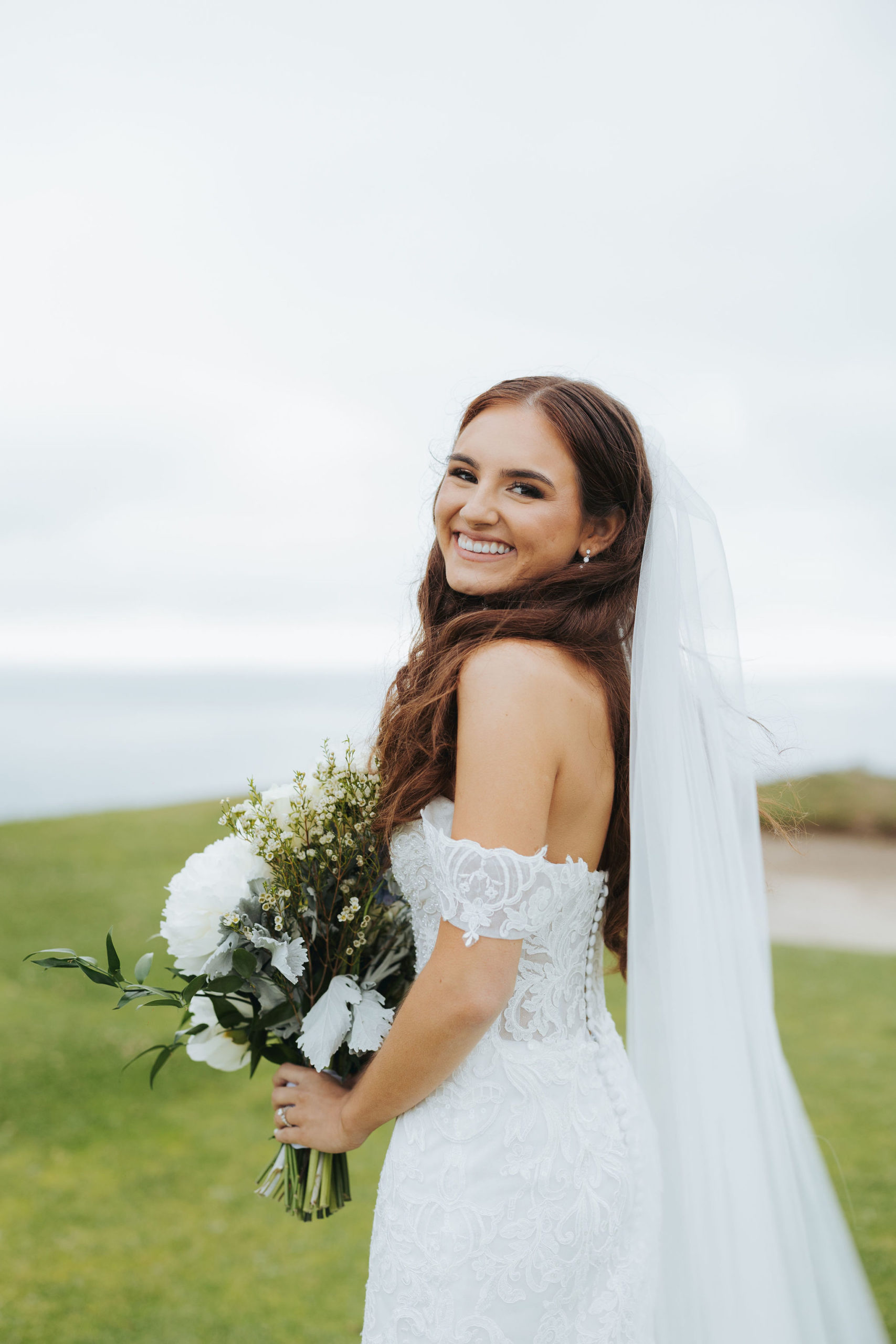 bride standing on golf course with blue and white bouquet