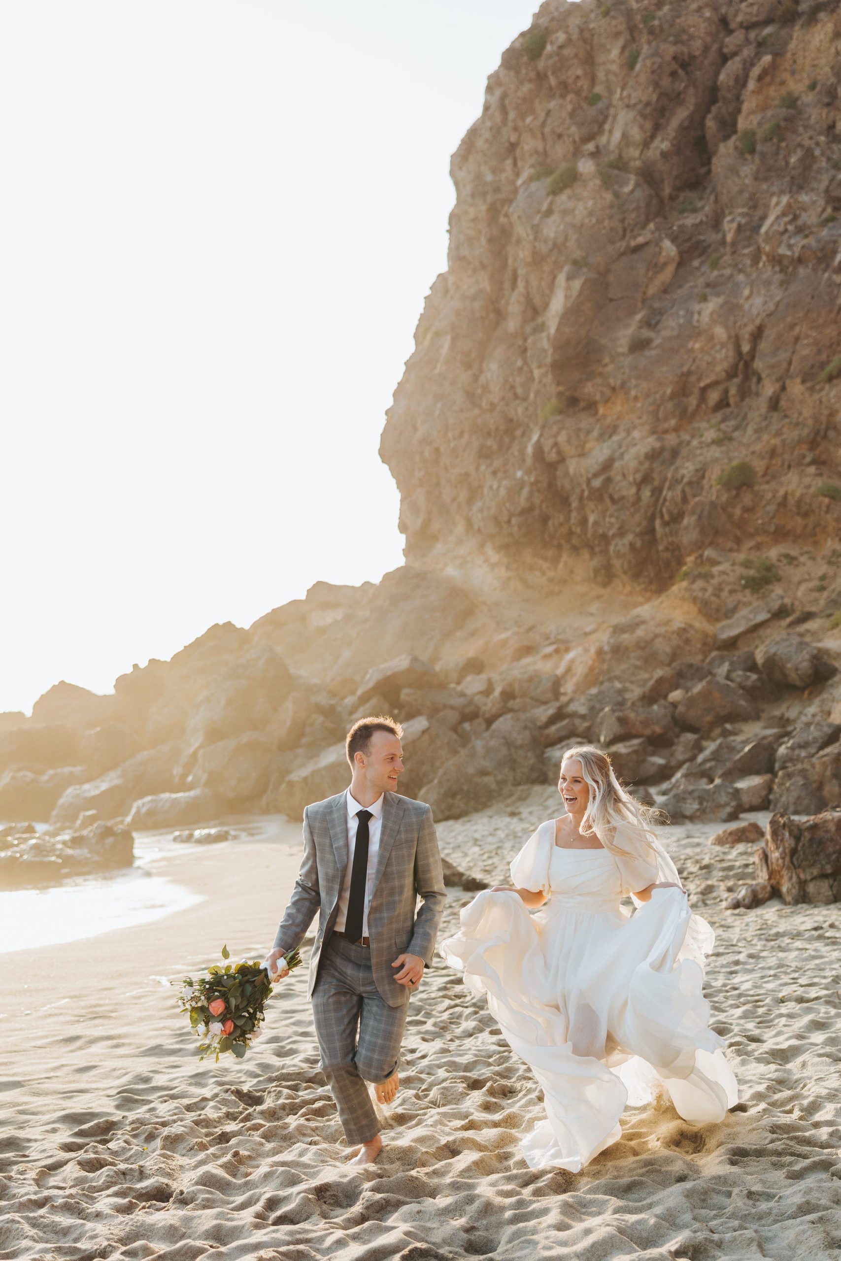 bride and groom holding hands walking on a beach at Point Dume