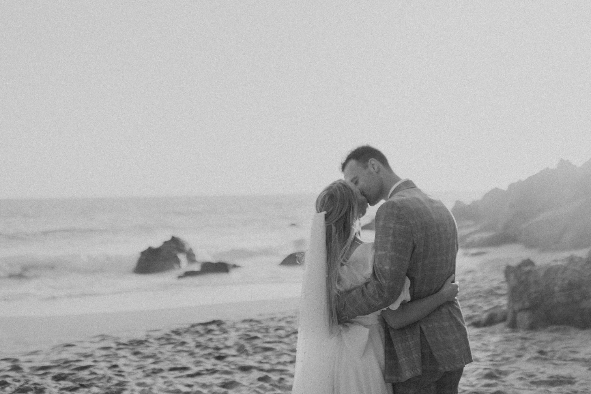 bride and groom kissing on a beach golden hour