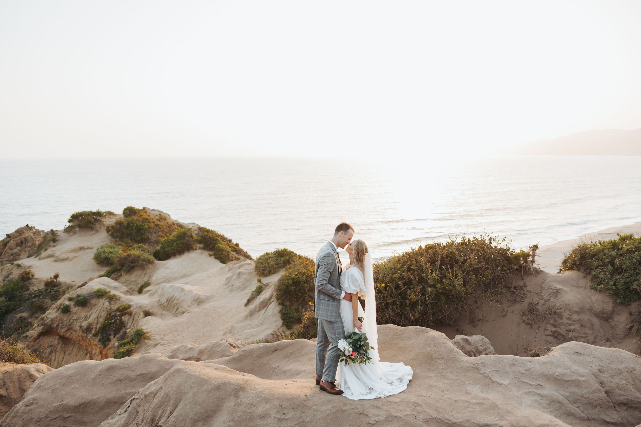 bride and groom hugging on a beach cliff at Point Dume