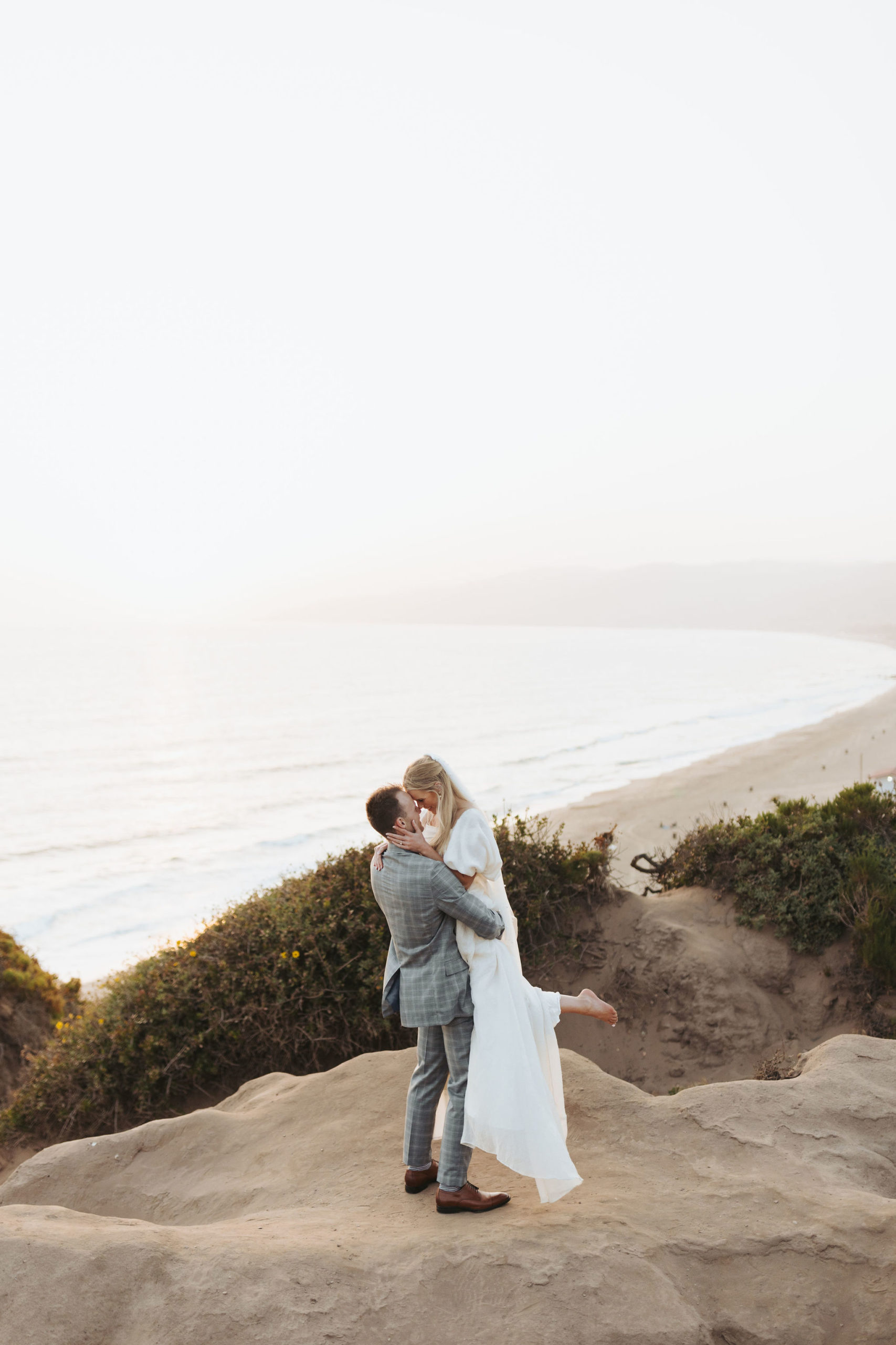 bride and groom hugging on a beach cliff at Point Dume