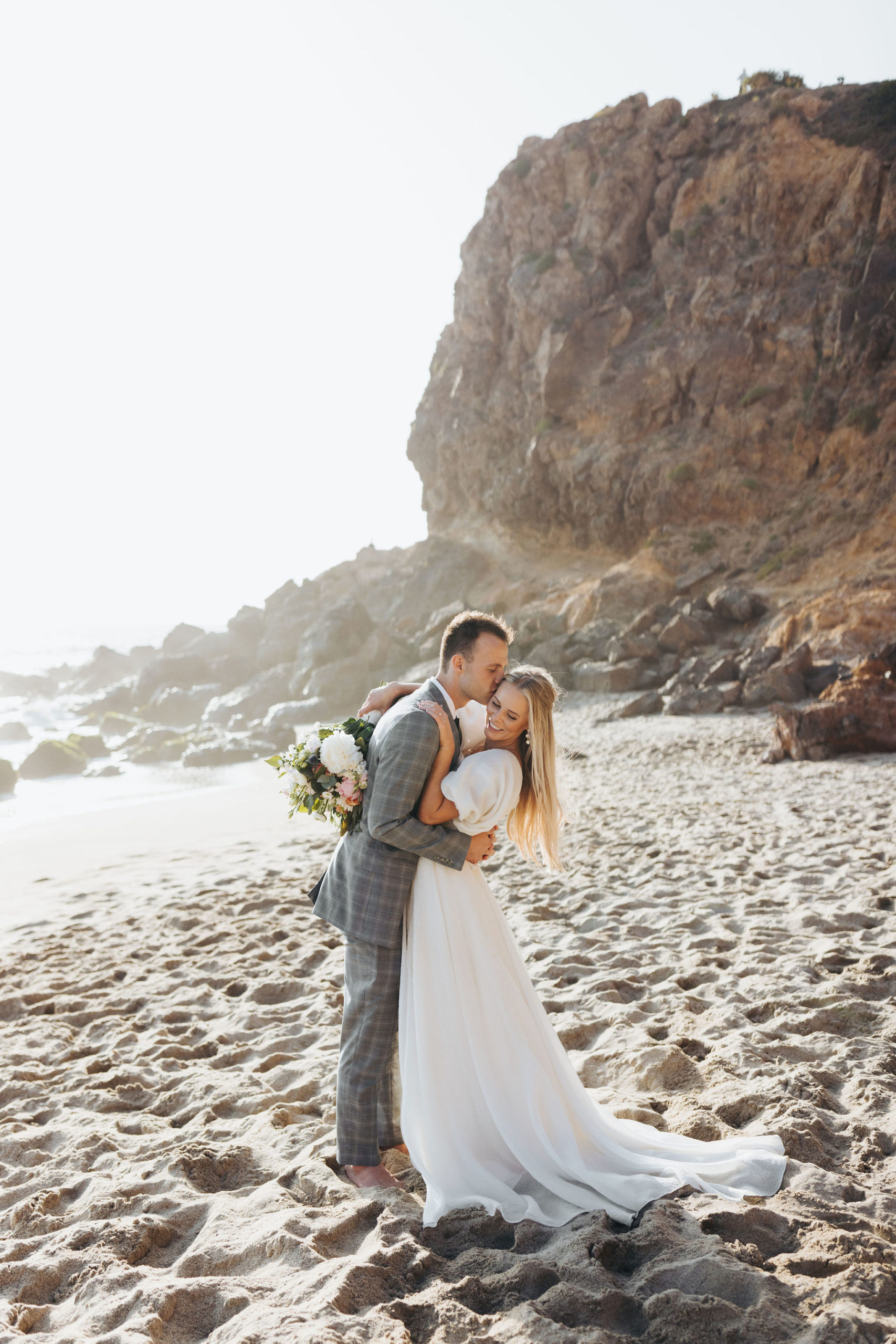 bride and groom hugging on a beach