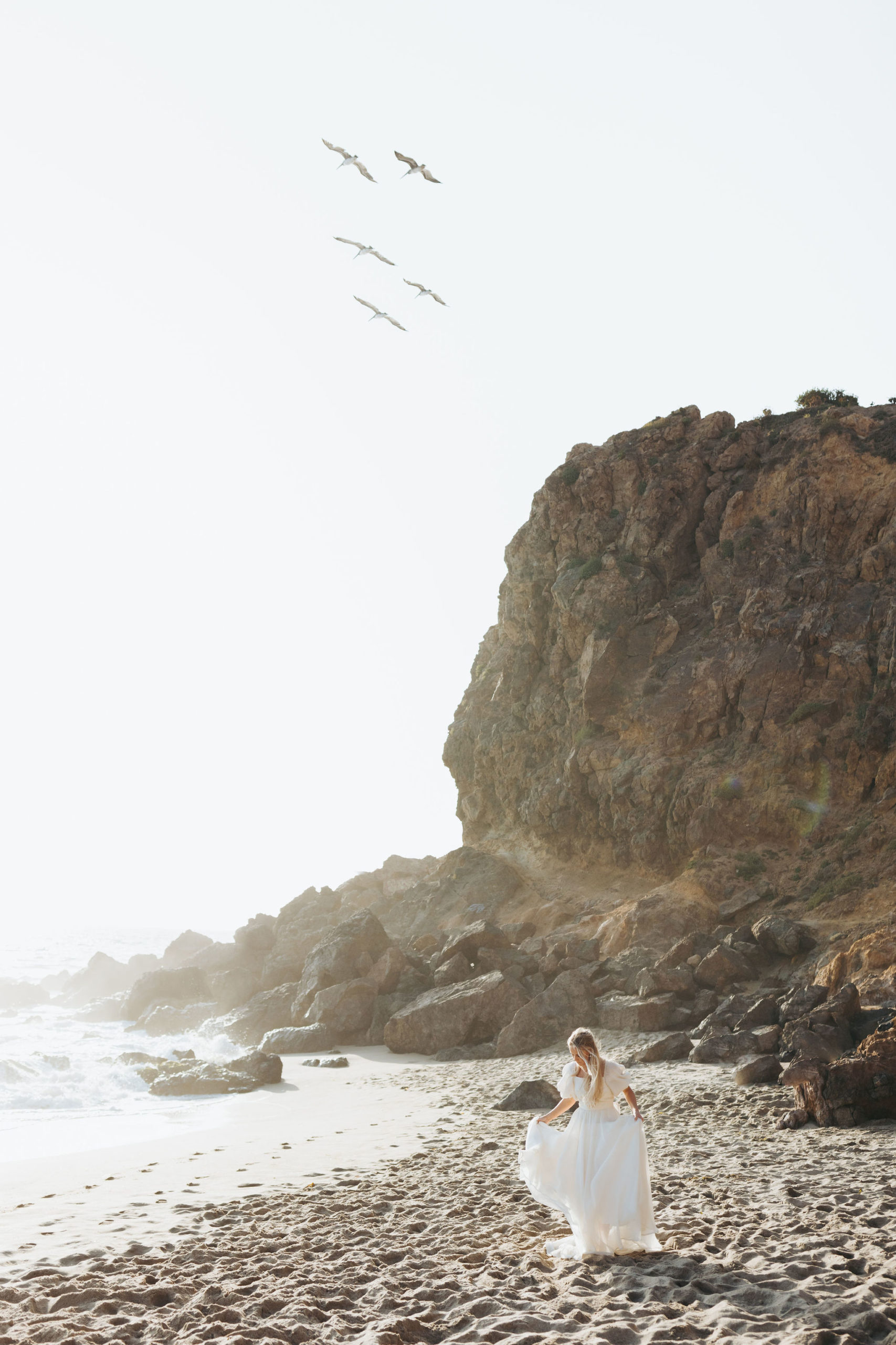 bride walking on a beach in front of rocks at Point Dume