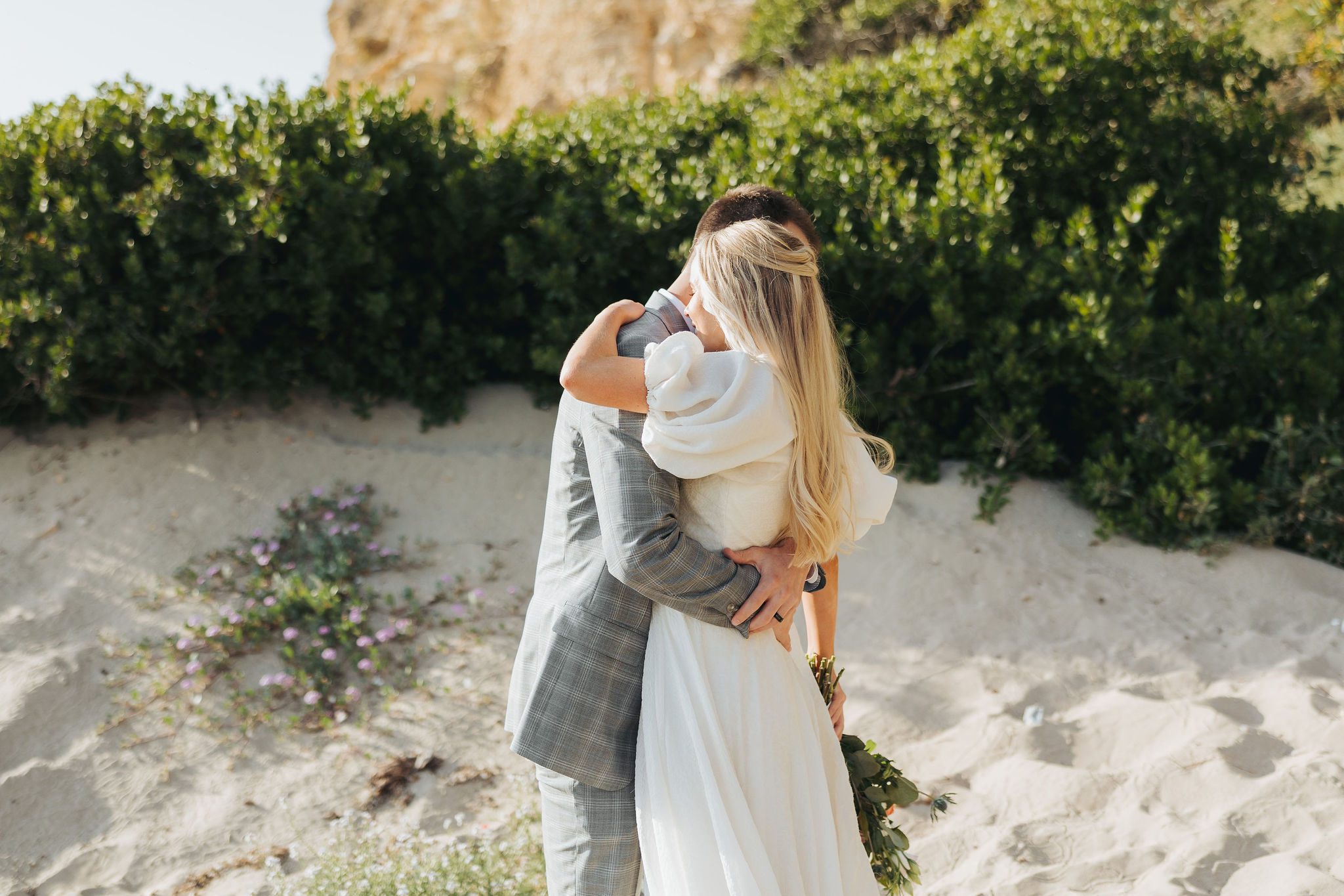 bride and groom holding hugging on a beach