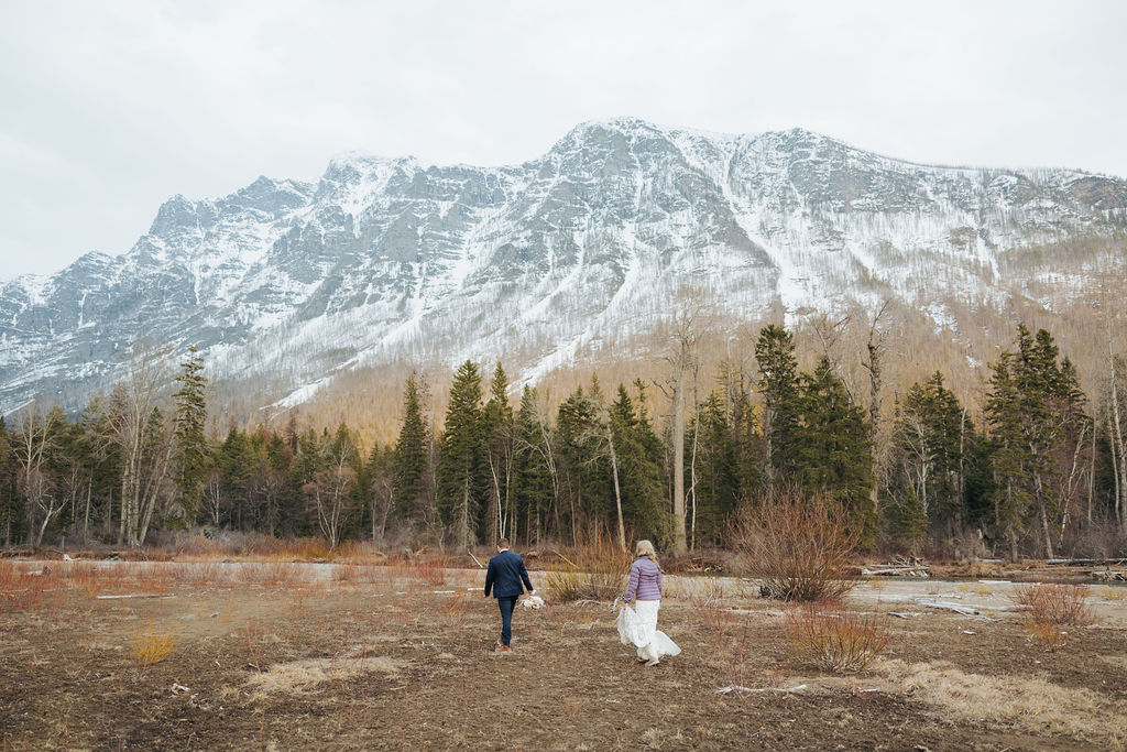 bride and groom walking at glacier national park in front of mountains
