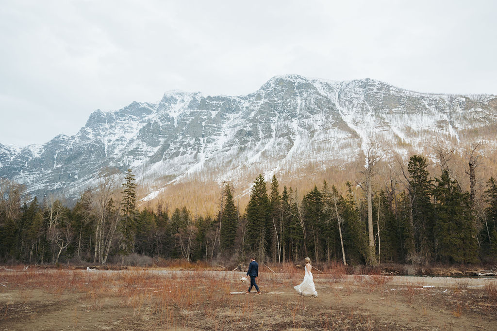 bride and groom walking at glacier national park in front of mountains