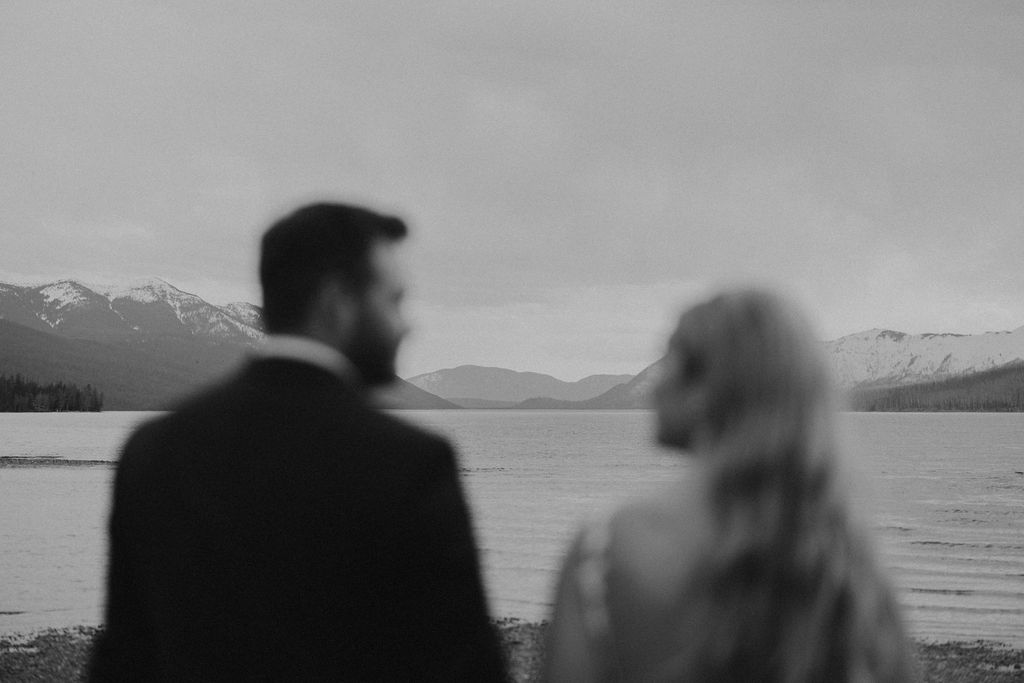 bride and groom walking on glacier national park lake with mountains in the background