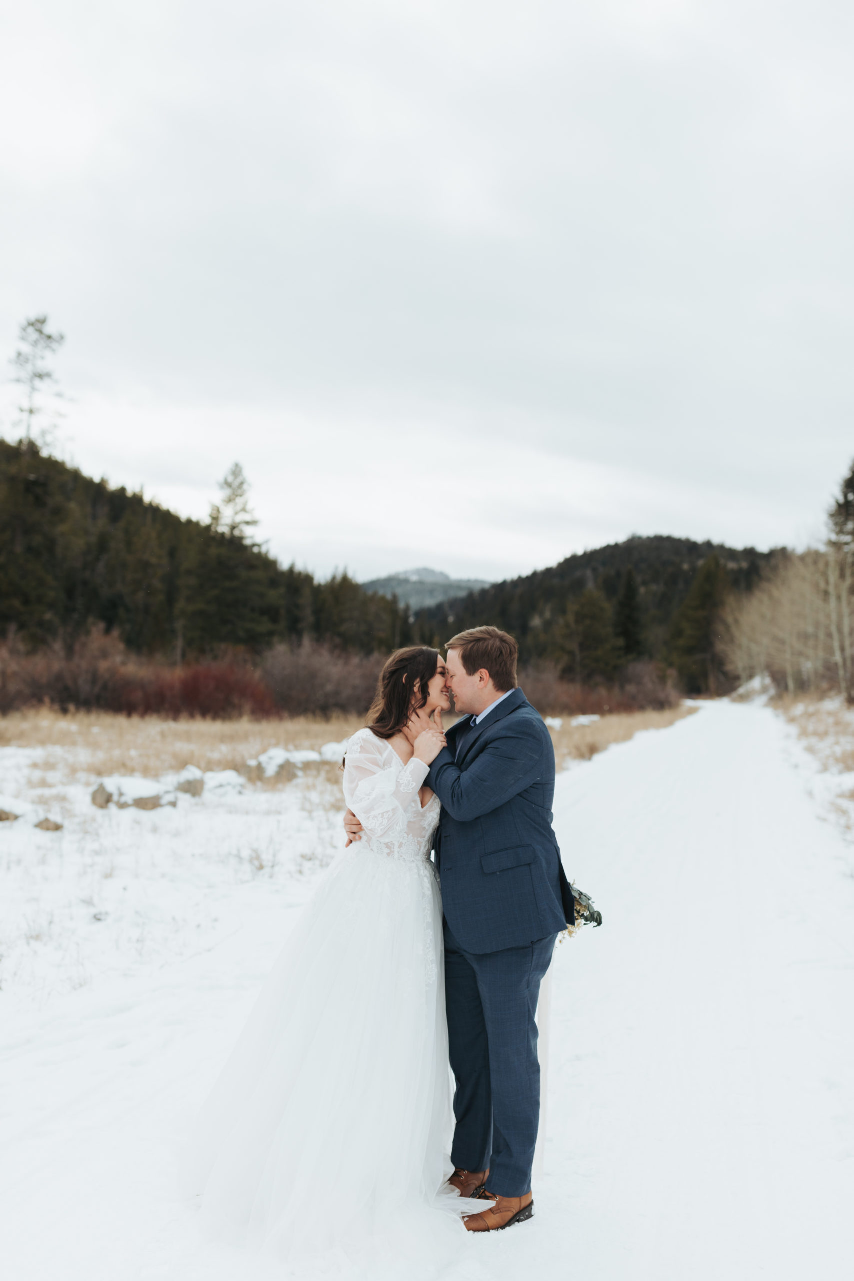 bride and groom kissing in snow and mountains after elopement ceremony in grand teton national park 