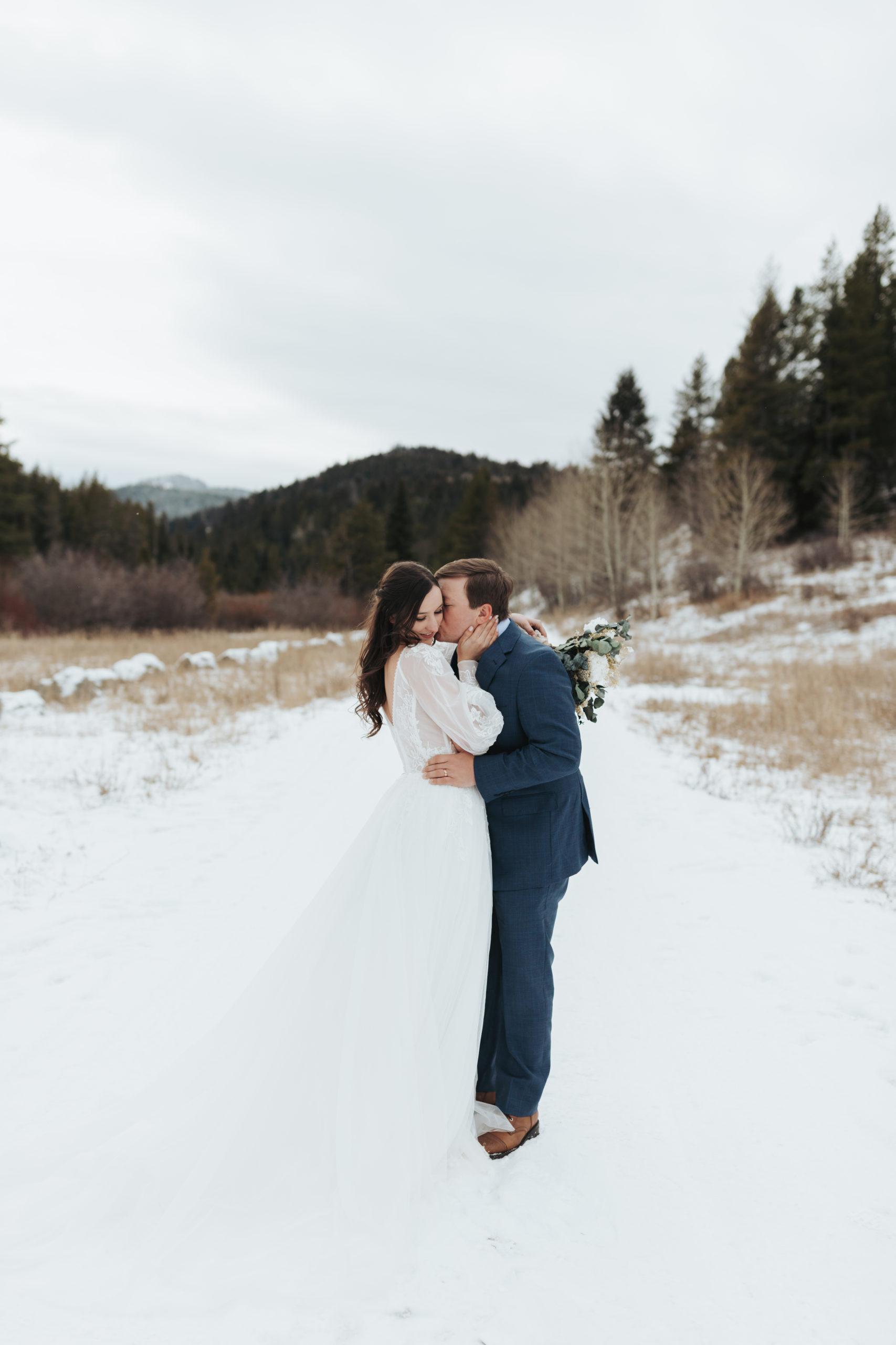 bride and groom kissing in snow and mountains in grand teton national park 
