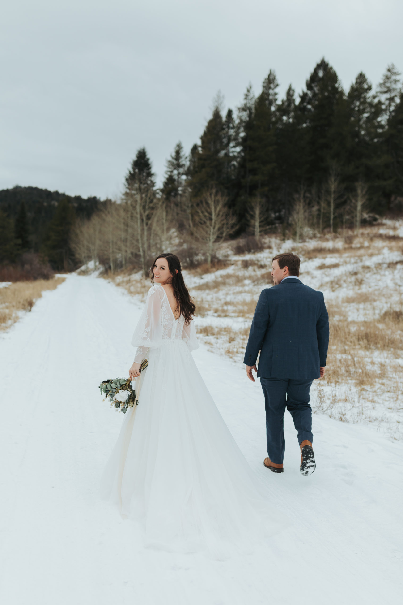 bride and groom walking in snow and mountains in grand teton national park 