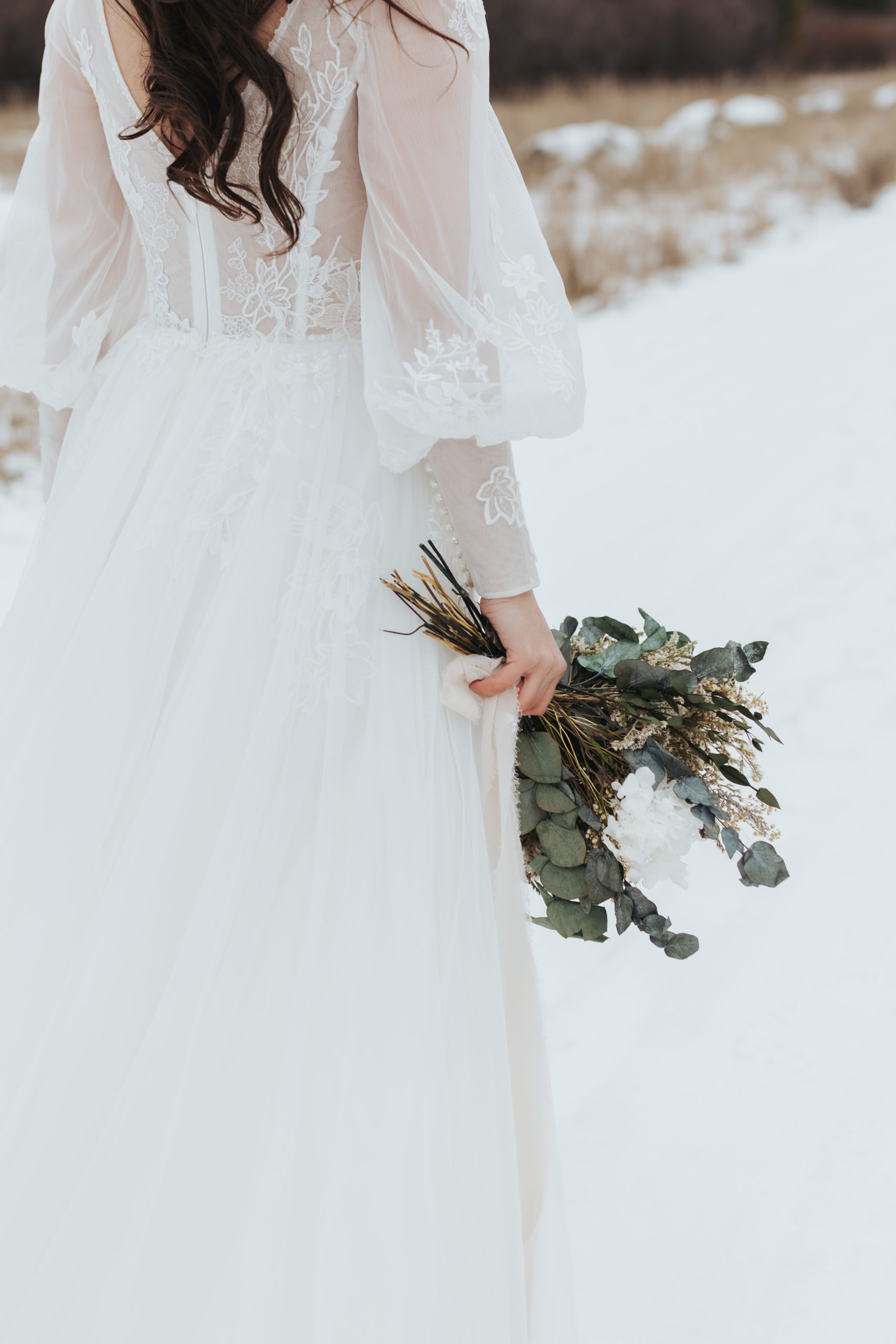 bride walking in snow with eucalyptus bouquet after elopement ceremony in grand teton national park 