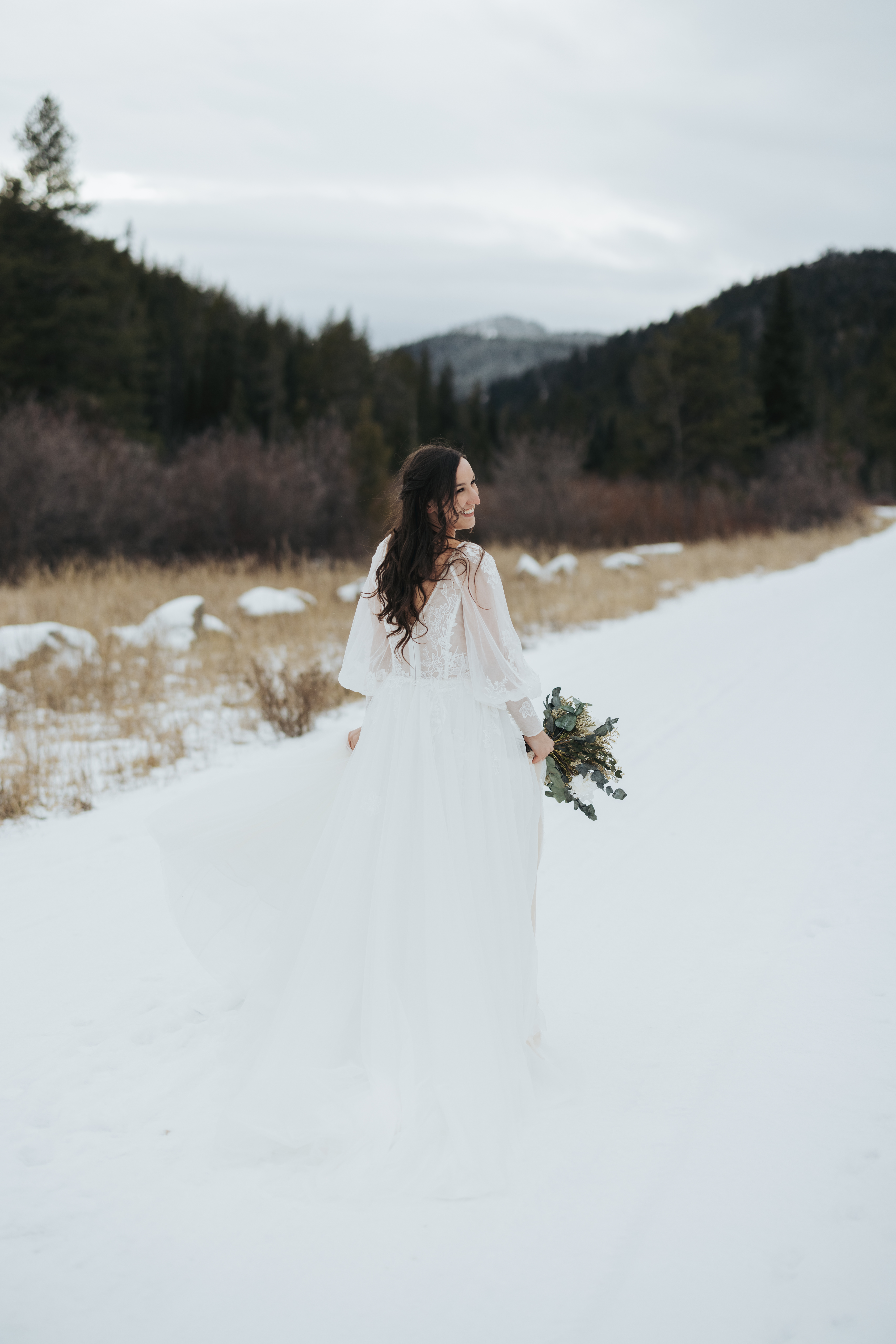 bride walking in snow with eucalyptus bouquet