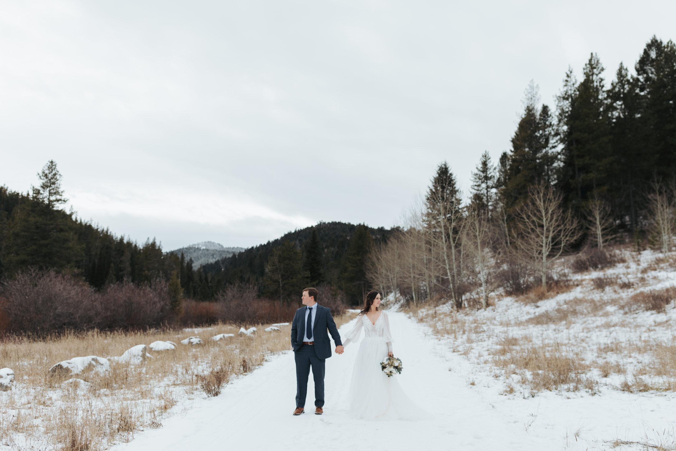 bride and groom walking in snow and mountains in grand teton national park 