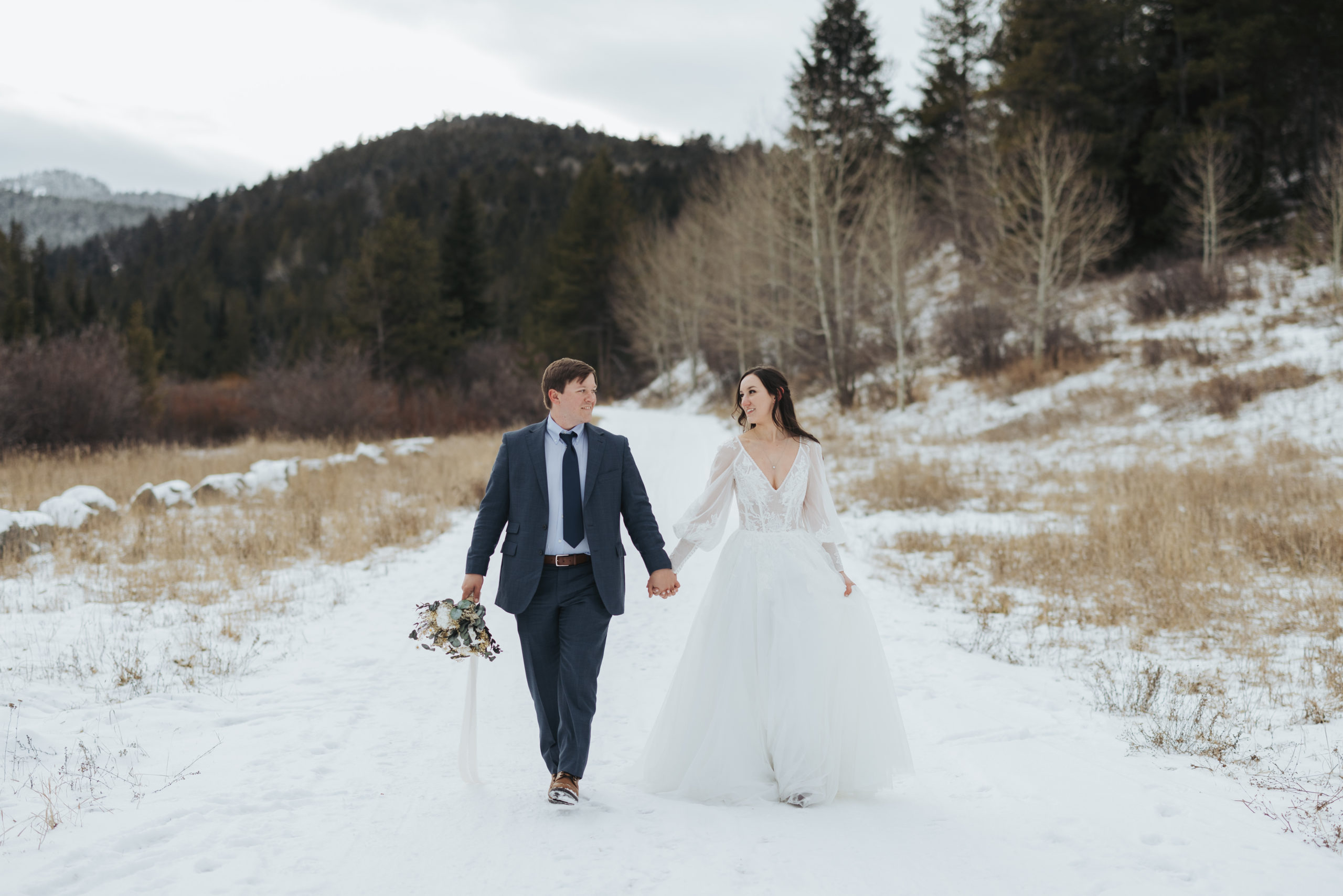 bride and groom walking in snow and mountains