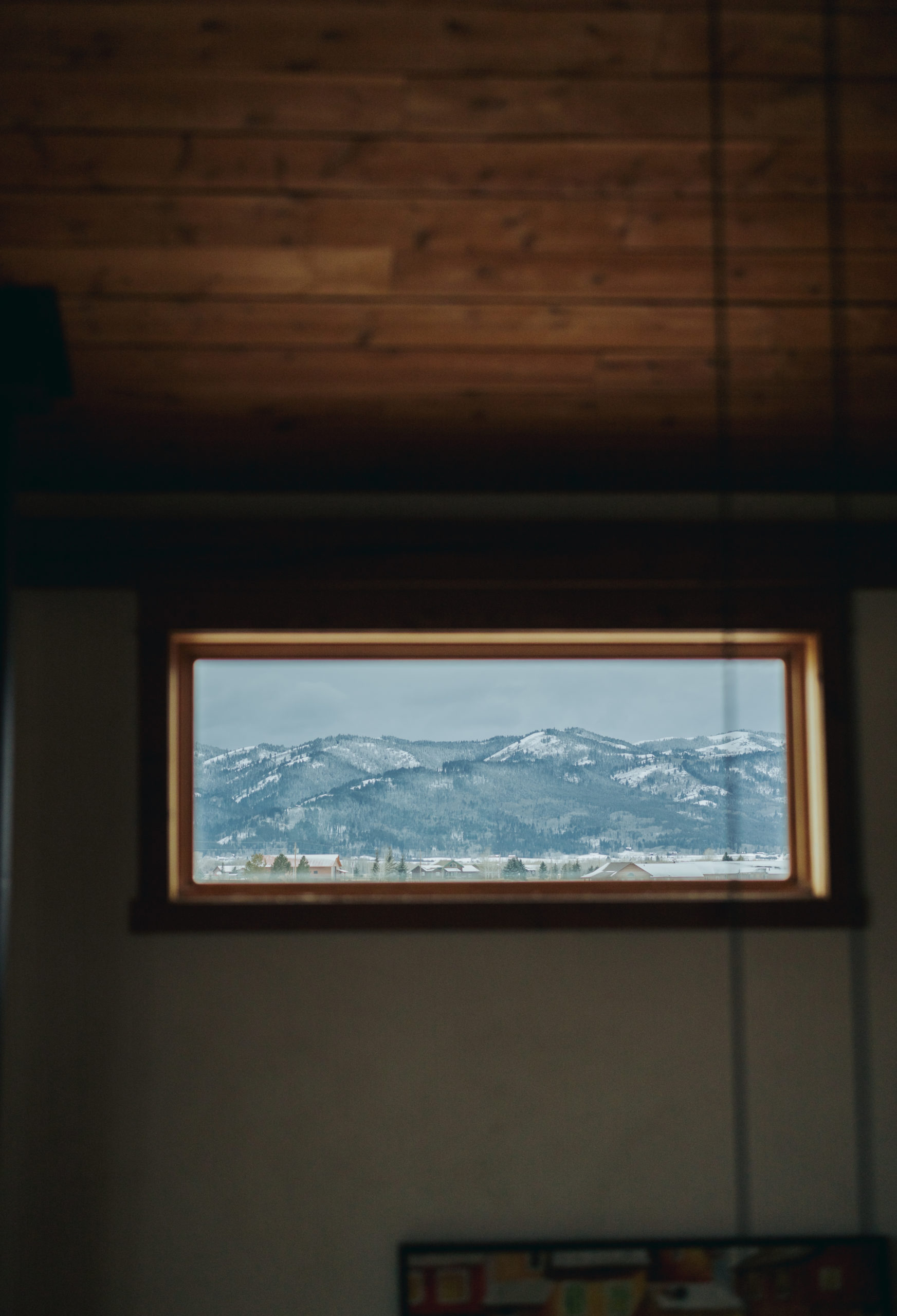 window of cabin looking at grand teton snowy mountains
