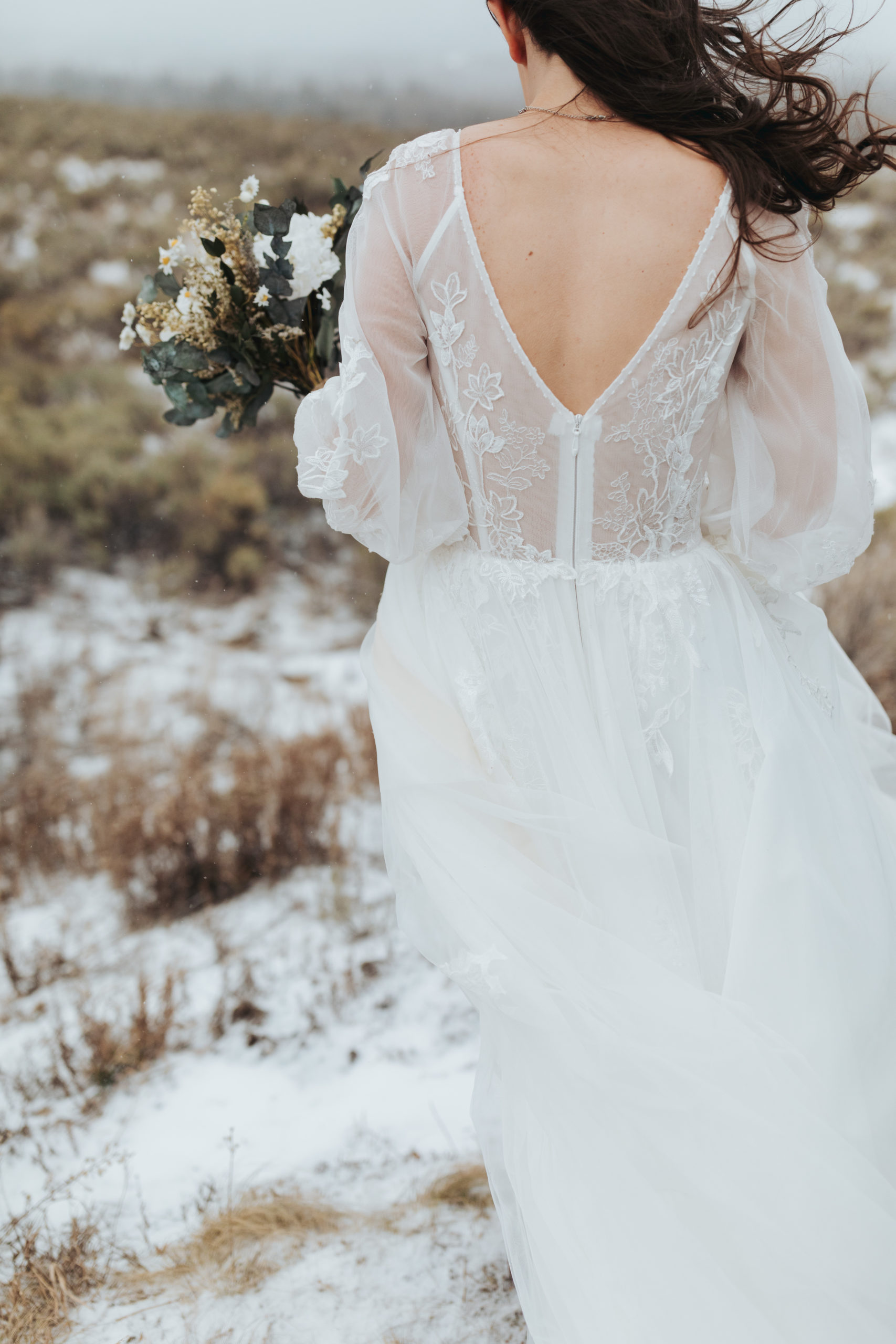 bride walking and holding snowy wedding bouquet after elopement ceremony in grand teton national park 