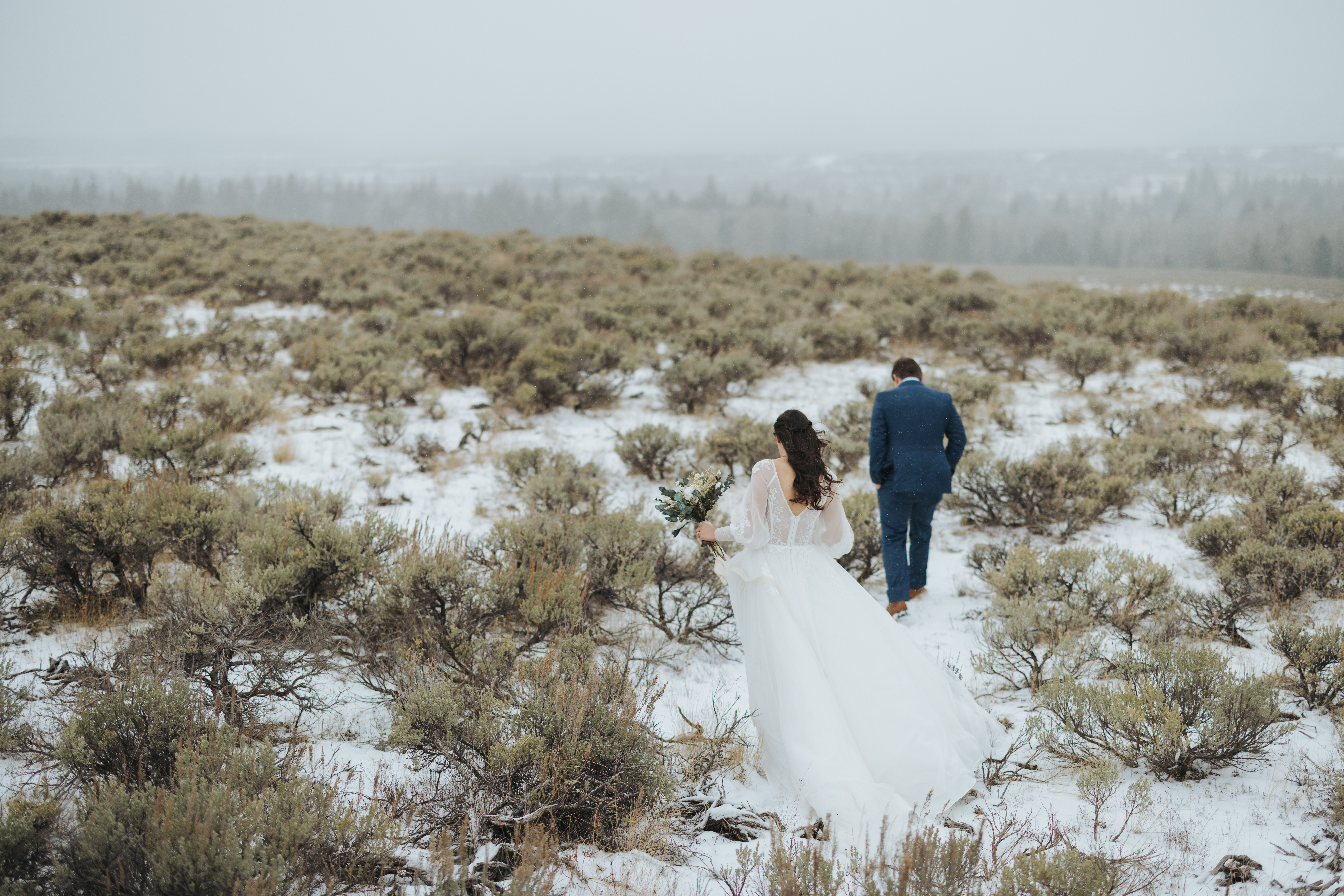 bride and groom walking in snow and mountains after elopement ceremony in grand teton national park 
