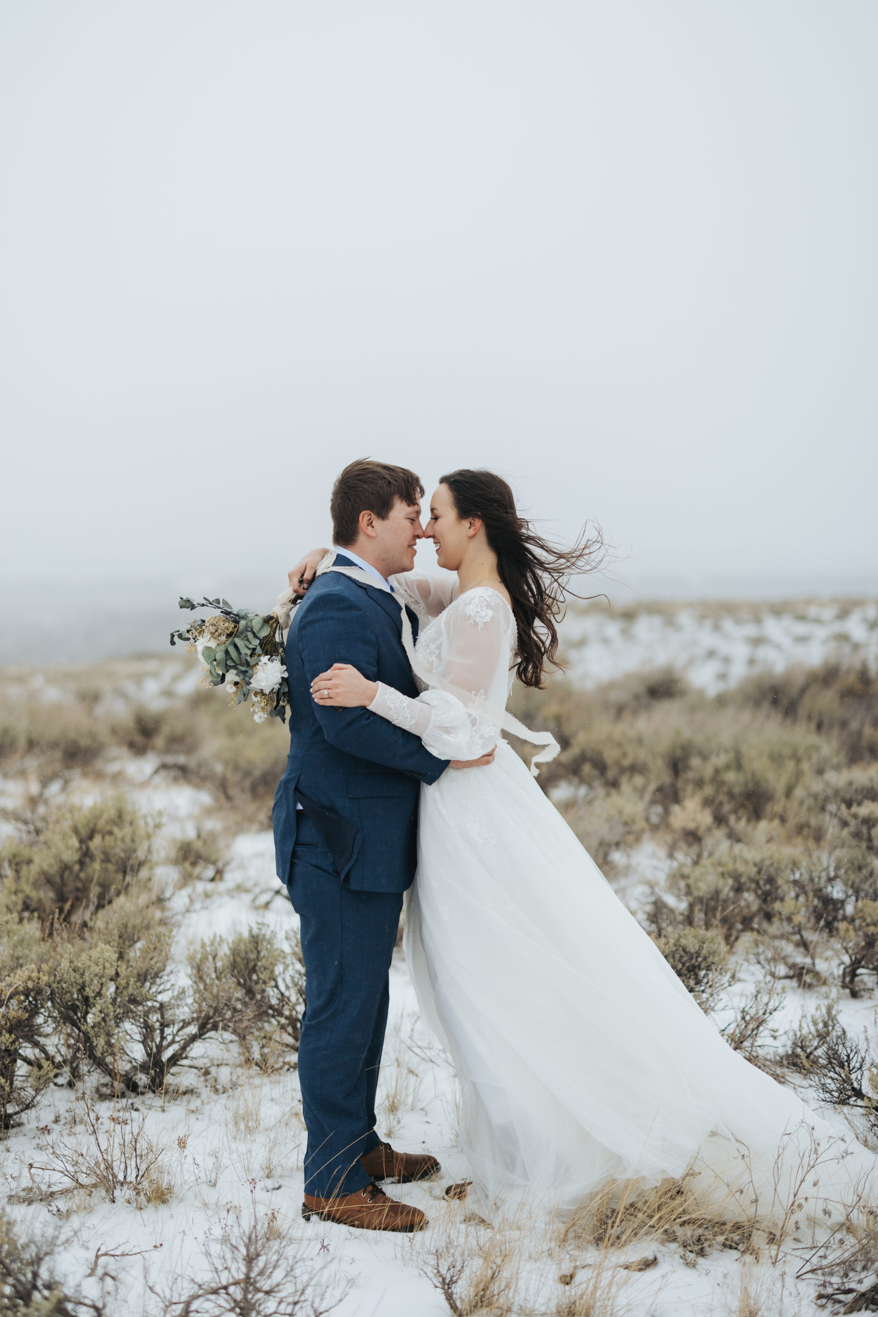 bride and groom hugging in snow and mountains after elopement ceremony in grand teton national park 
