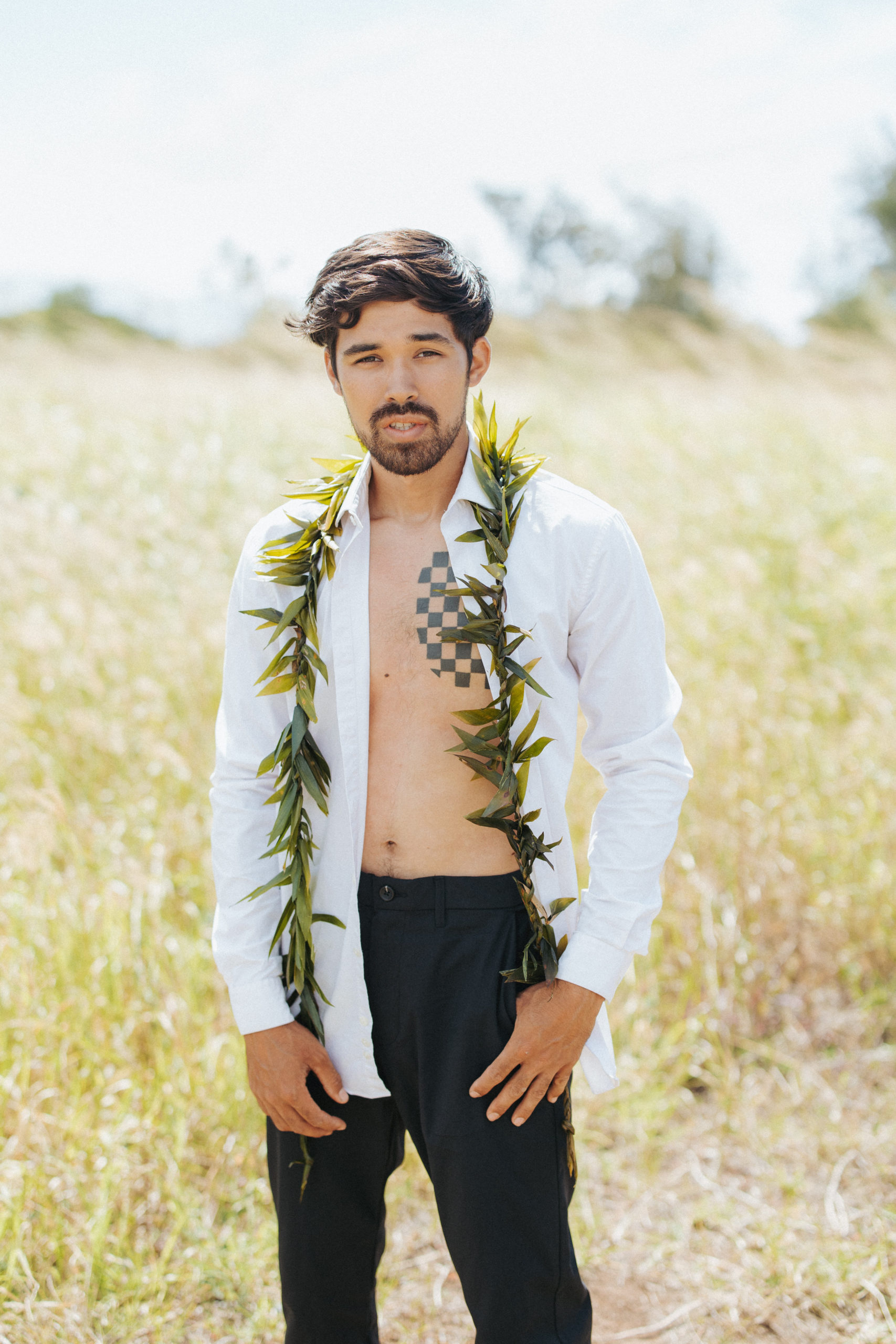 groom standing in a field couple portrait in hawaii