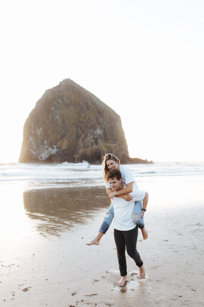 woman piggy backing on man's back at the beach in Cannon Beach Oregon