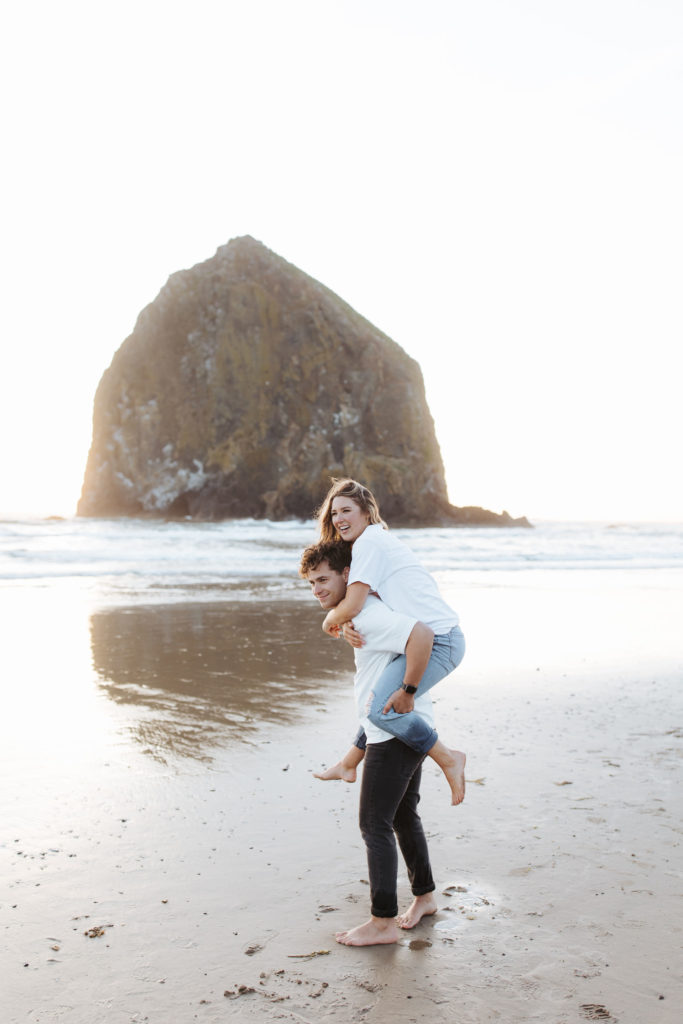 woman piggy backing on man's back at the beach in Cannon Beach Oregon