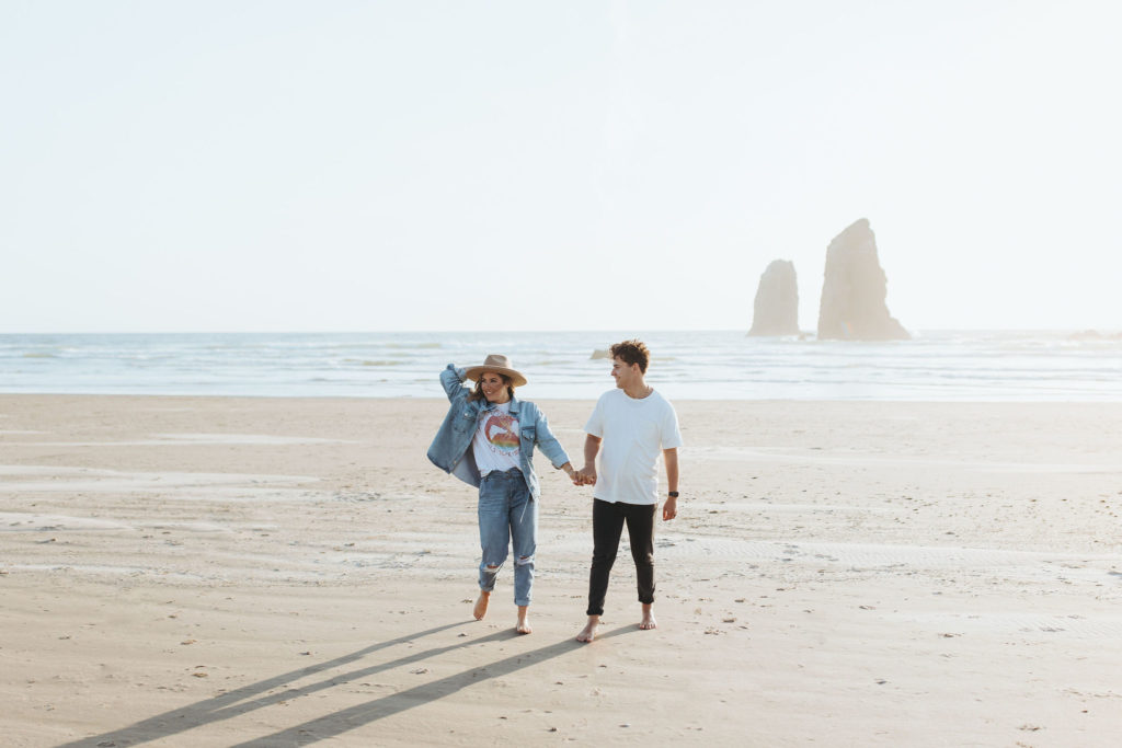 couple walking on the beach holding hands in Cannon Beach Oregon