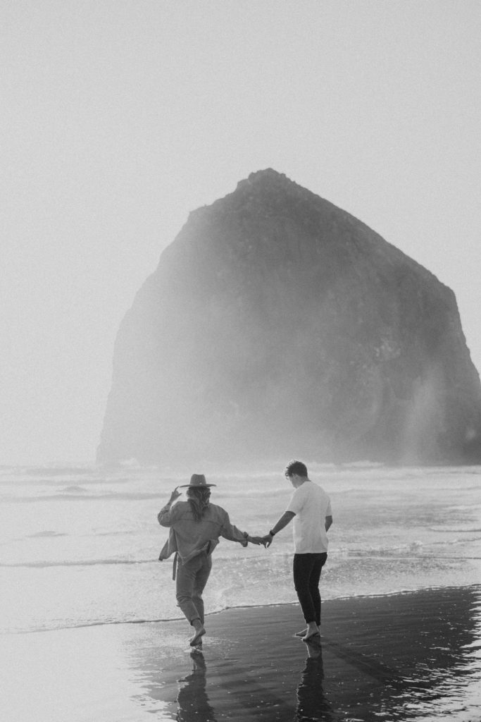 couple walking on the beach in black and white 