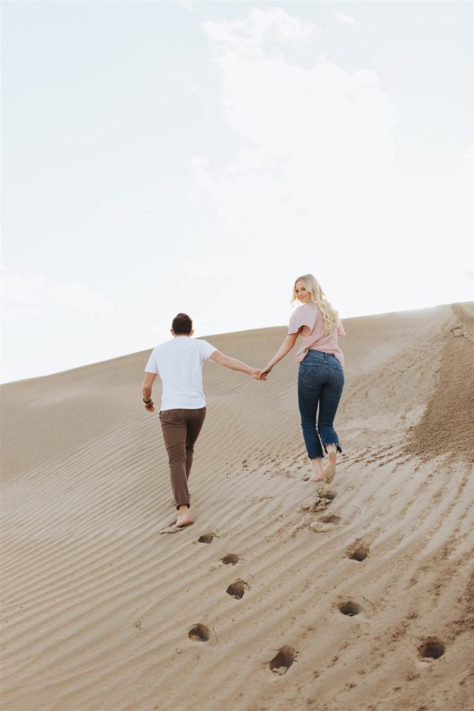 Couple walking on the sand dune for their engagement session