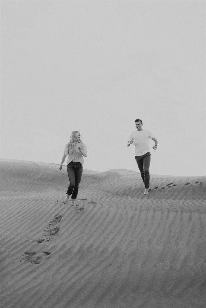 Couple walking on the sand dune for their engagement session 