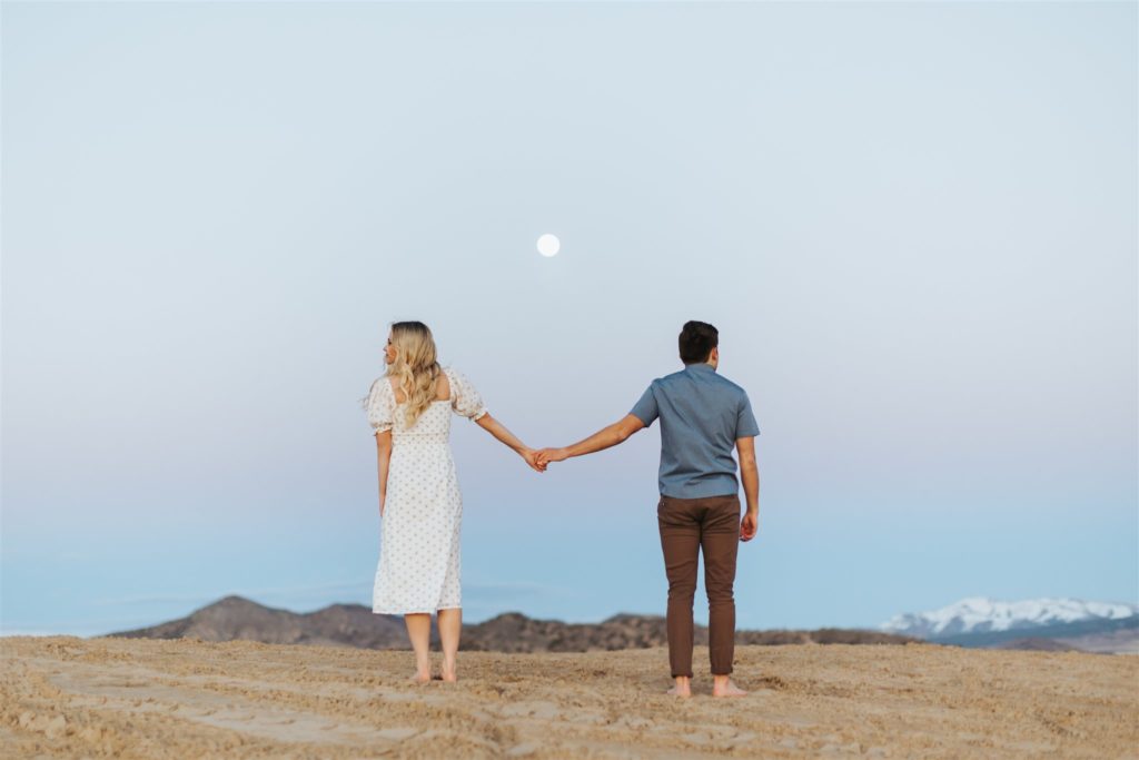 Couple walking on sand dune in front of mountains
