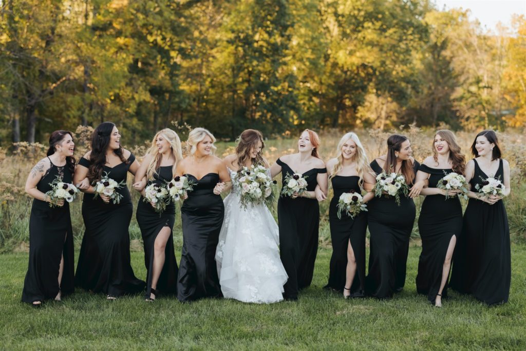 bride with lace wedding dress and bridesmaids in a field